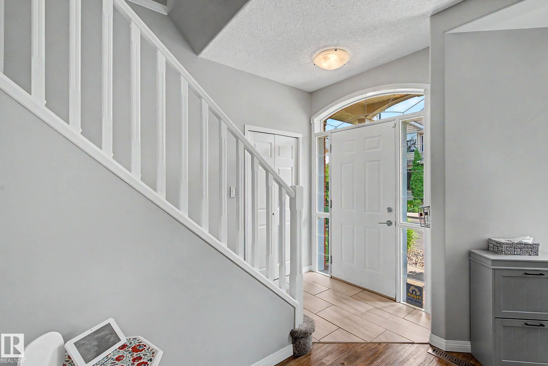 Inviting entryway featuring a white paneled door with an arched transom, sidelight windows, and a combination of wood-finish and tiled flooring - 9130 100A Avenue Nw, Edmonton, AB - Indoor Photo Showing Other Room
