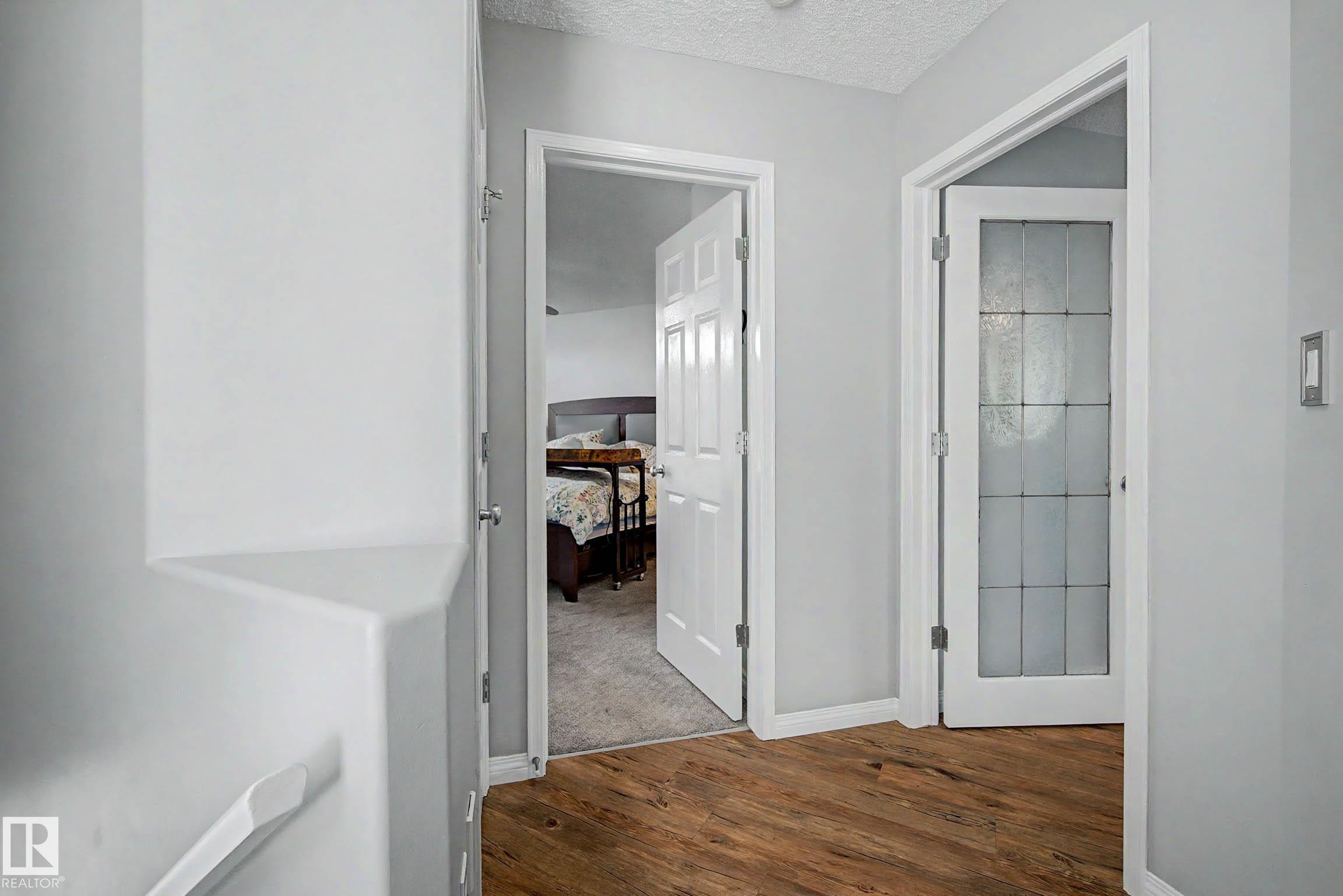Hallway with wood-finish flooring, light grey wall paint, and white trim - 9130 100A Avenue Nw, Edmonton, AB - Indoor Photo Showing Other Room