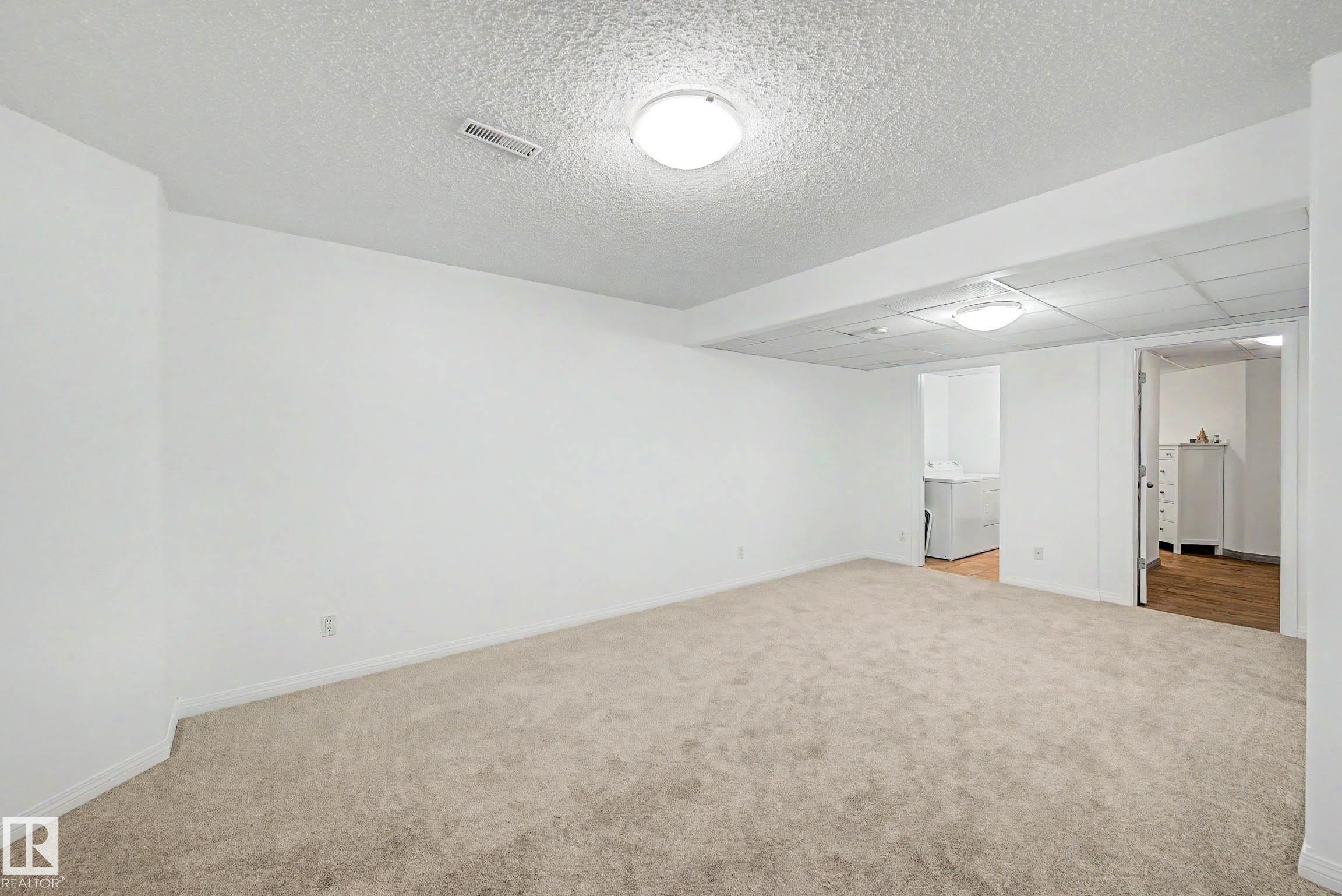 Expansive carpeted room with white walls, recessed lighting, and a white drop ceiling - 9130 100A Avenue Nw, Edmonton, AB - Indoor Photo Showing Other Room