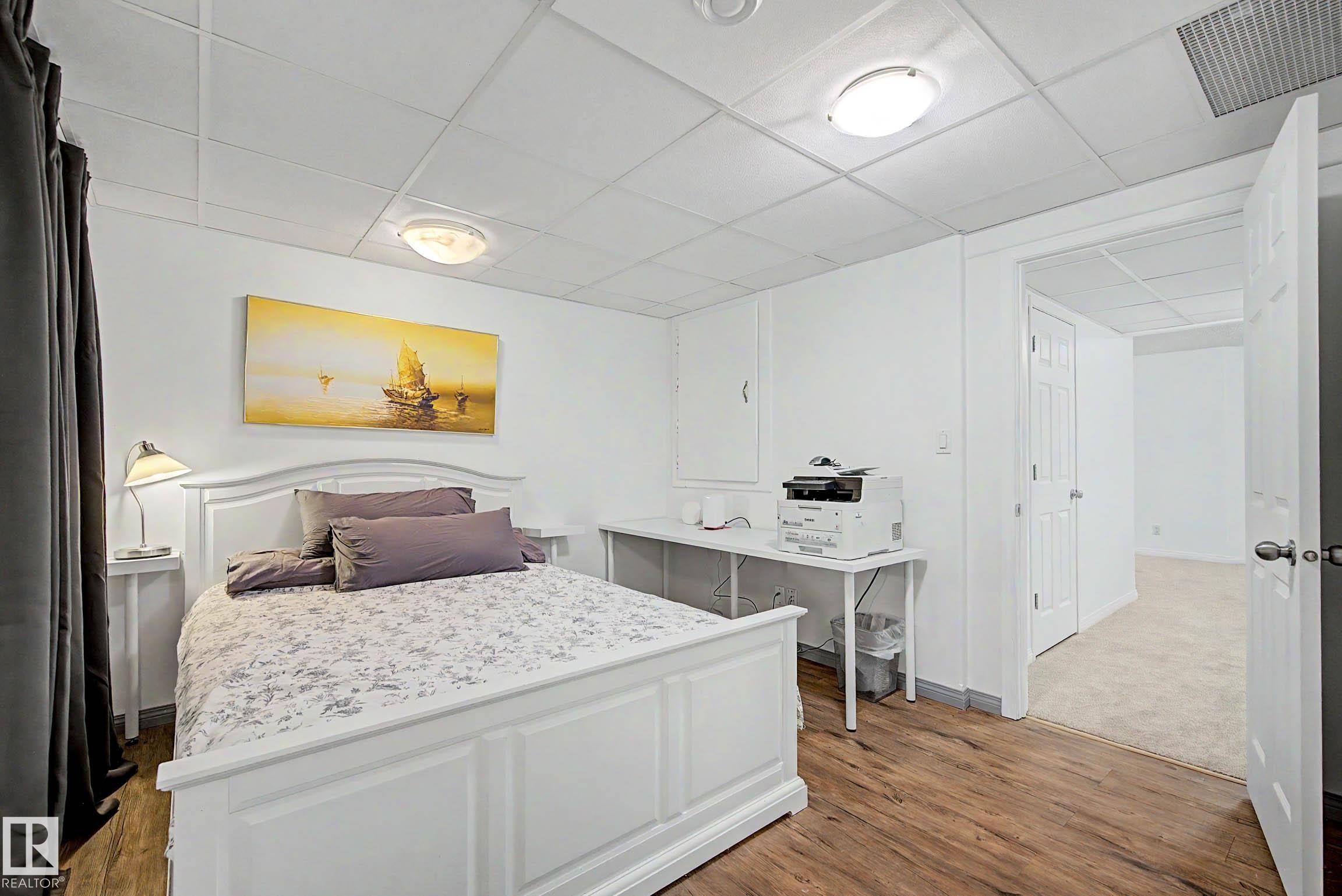 Interior room with wood-finish flooring, white walls, and a white grid ceiling - 9130 100A Avenue Nw, Edmonton, AB - Indoor