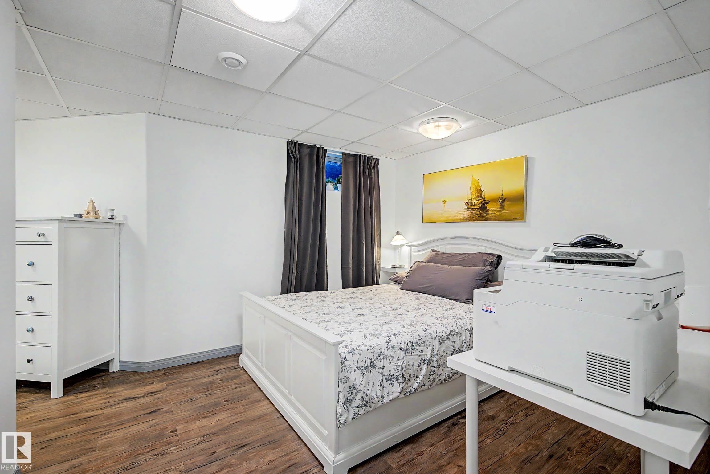 Spacious room featuring wood-finish flooring, white walls, and a drop ceiling with recessed lighting - 9130 100A Avenue Nw, Edmonton, AB - Indoor Photo Showing Bedroom