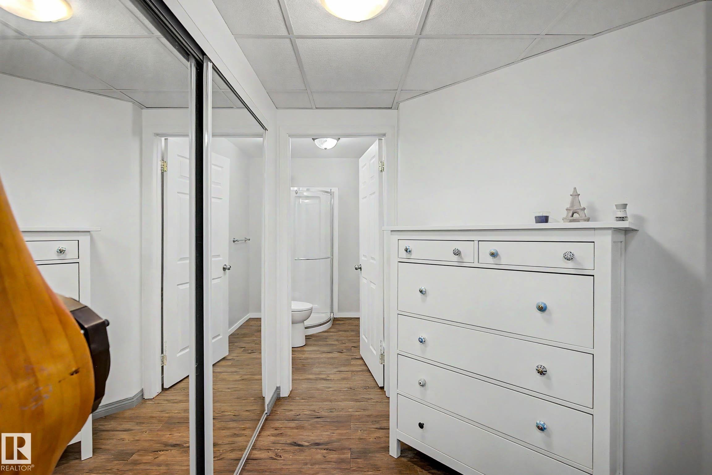 Interior space featuring wood-finish flooring, white walls, and a white grid ceiling - 9130 100A Avenue Nw, Edmonton, AB - Indoor Photo Showing Other Room