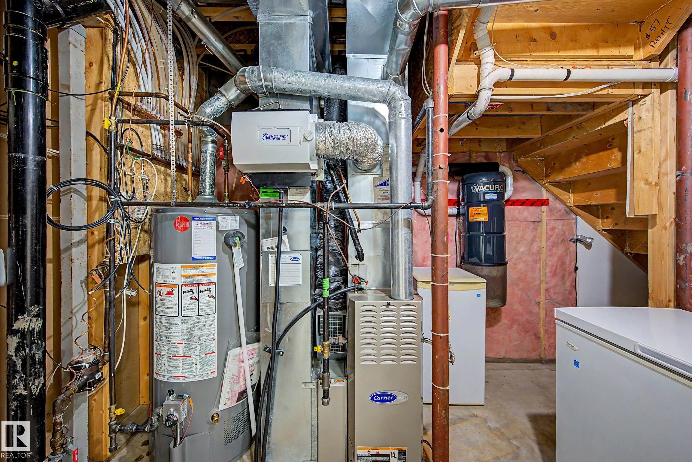 Utility area featuring a water heater, furnace, and exposed wood framing - 9130 100A Avenue Nw, Edmonton, AB - Indoor Photo Showing Basement