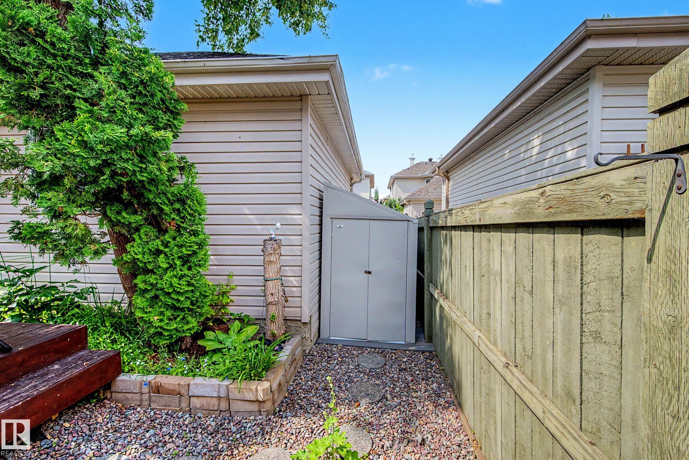 Side yard featuring gravel ground cover, a wooden privacy fence, and a garden shed - 9130 100A Avenue Nw, Edmonton, AB - Outdoor With Exterior