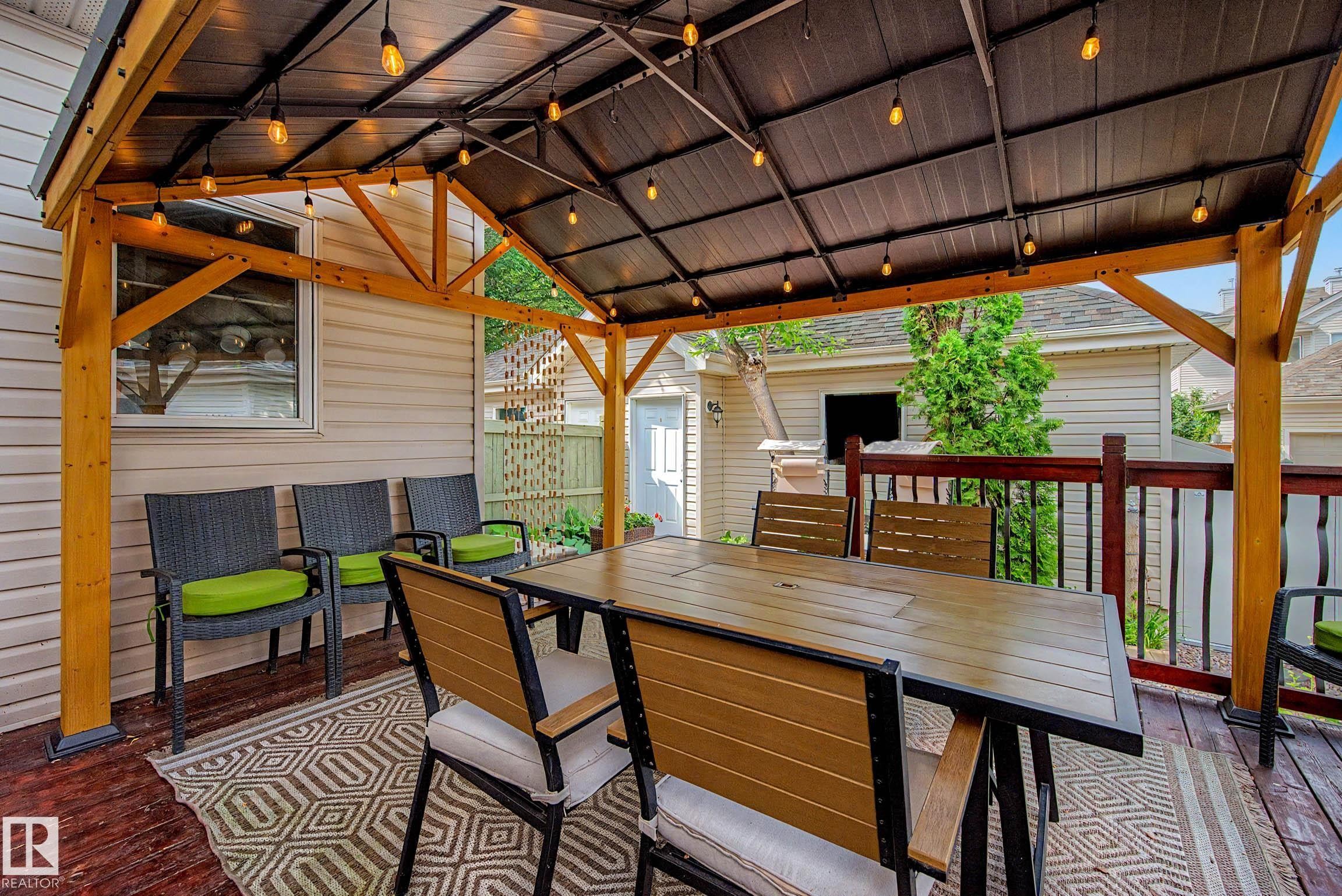 Covered outdoor deck featuring a dark composite roof and exposed wood-beam construction - 9130 100A Avenue Nw, Edmonton, AB - Outdoor With Deck Patio Veranda With Exterior