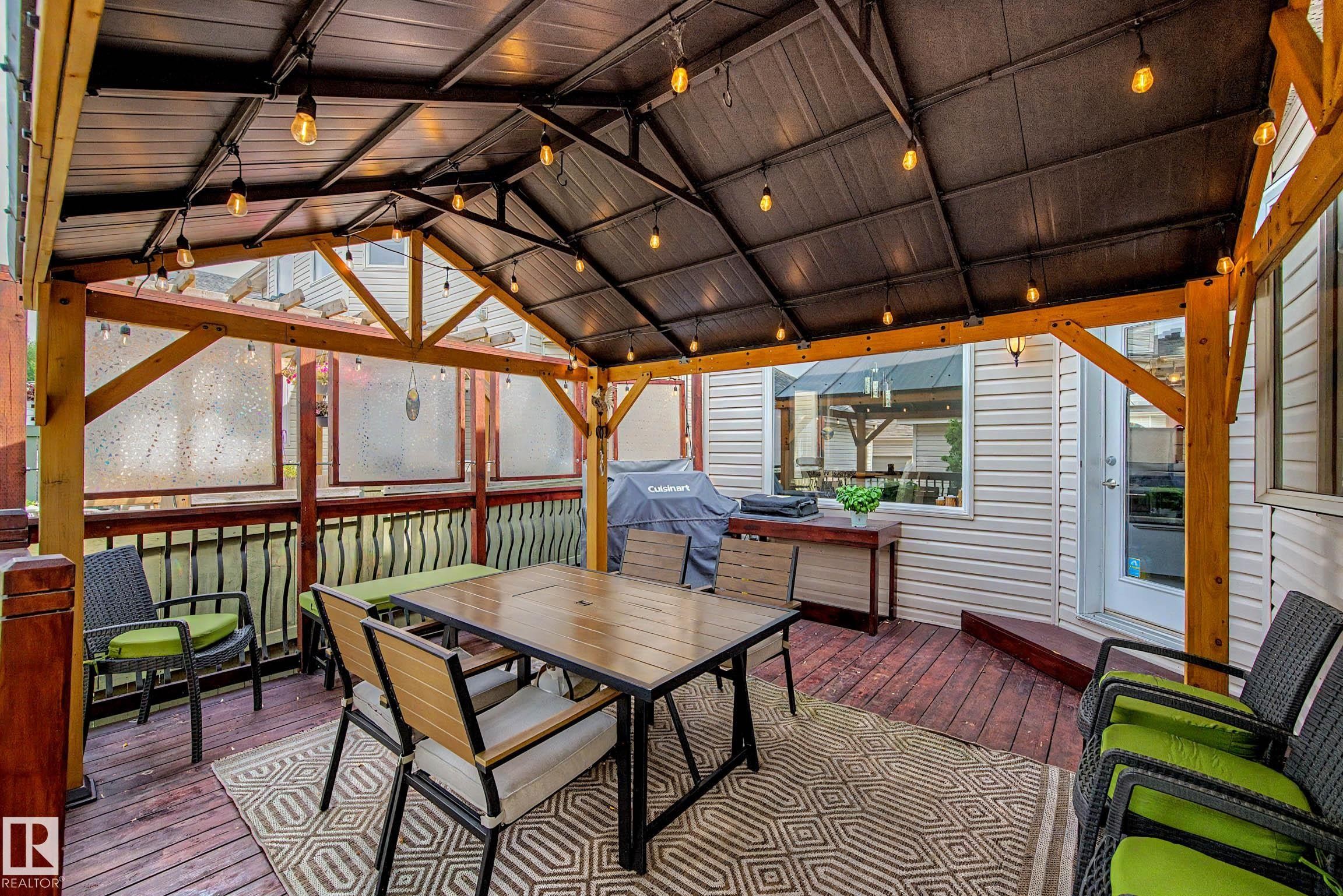Covered outdoor deck with string lighting - 9130 100A Avenue Nw, Edmonton, AB - Outdoor With Deck Patio Veranda With Exterior