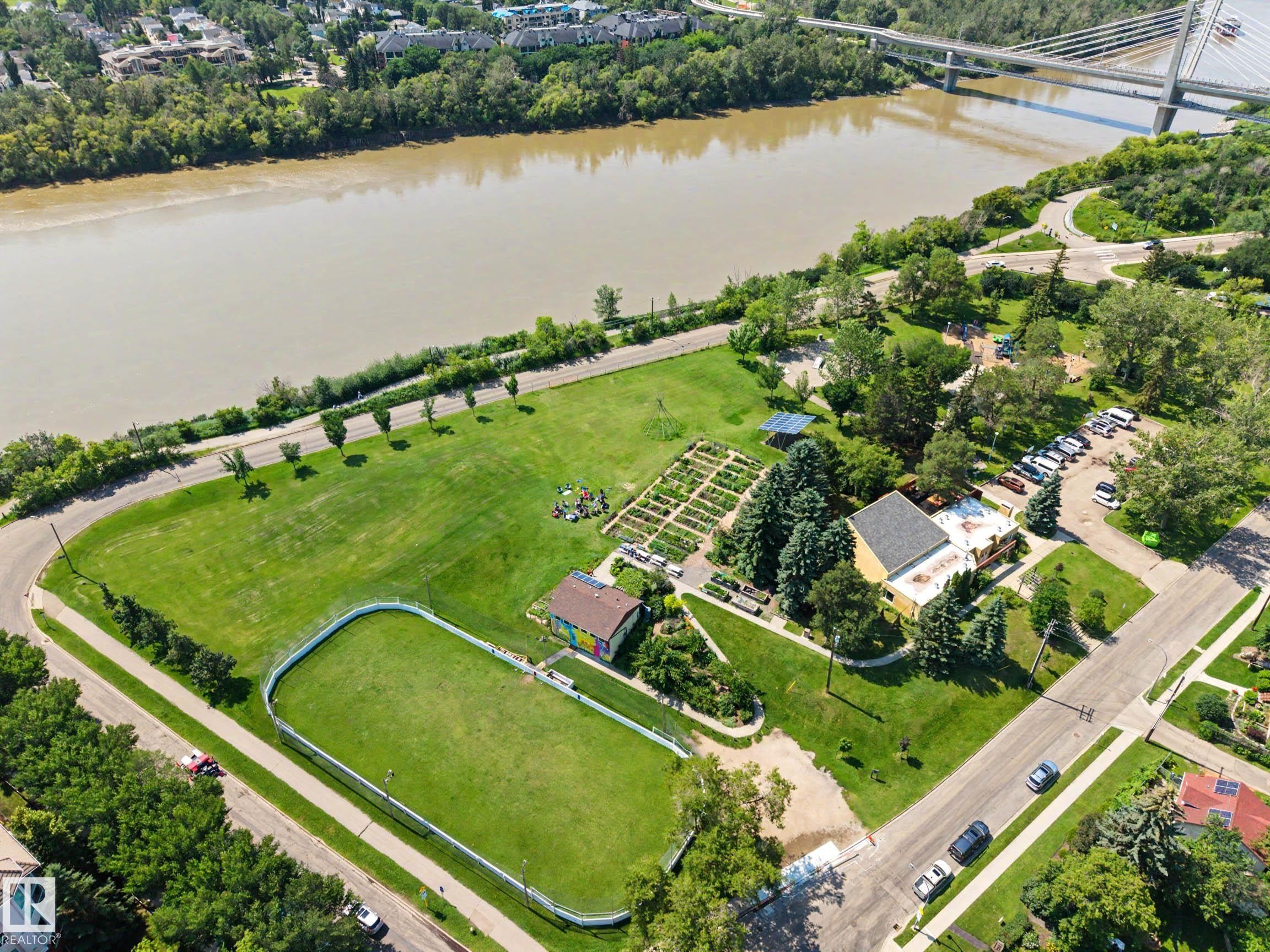 Expansive green spaces featuring a large, fenced turf area and manicured lawns - 9130 100A Avenue Nw, Edmonton, AB - Outdoor With Body Of Water With View