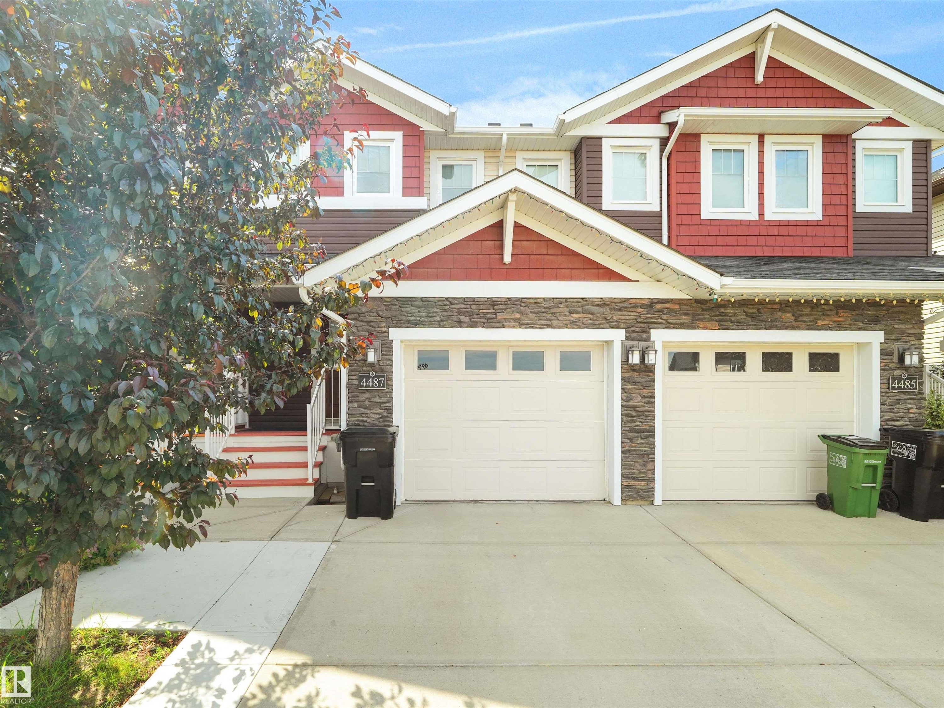 Contemporary exterior featuring stacked stone accents, red horizontal siding, and white trim - 4487 Annett Common Sw, Edmonton, AB - Outdoor