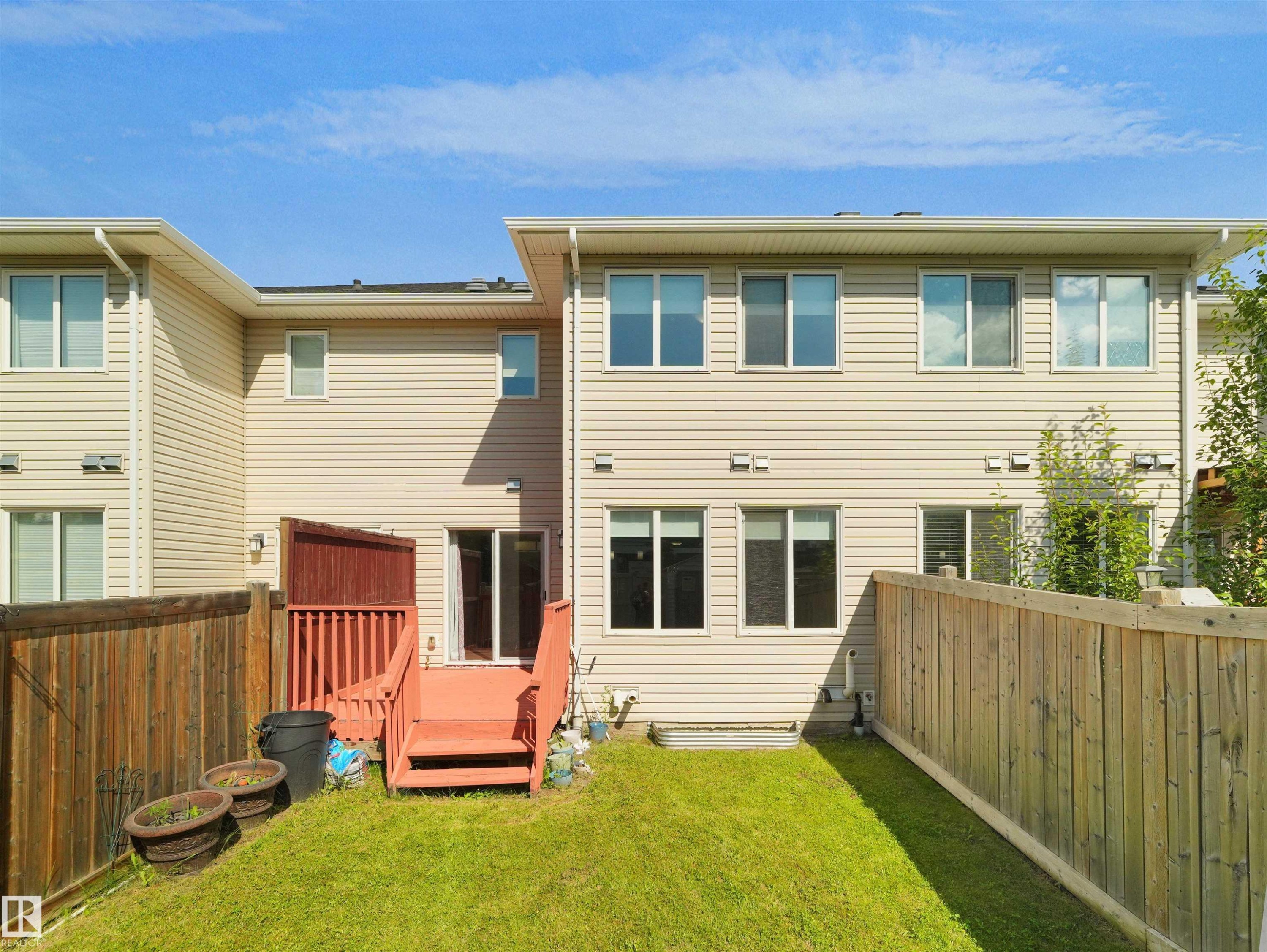 Fenced backyard featuring a manicured lawn, a wooden deck with railing, and a sliding glass door entry - 4487 Annett Common Sw, Edmonton, AB - Outdoor