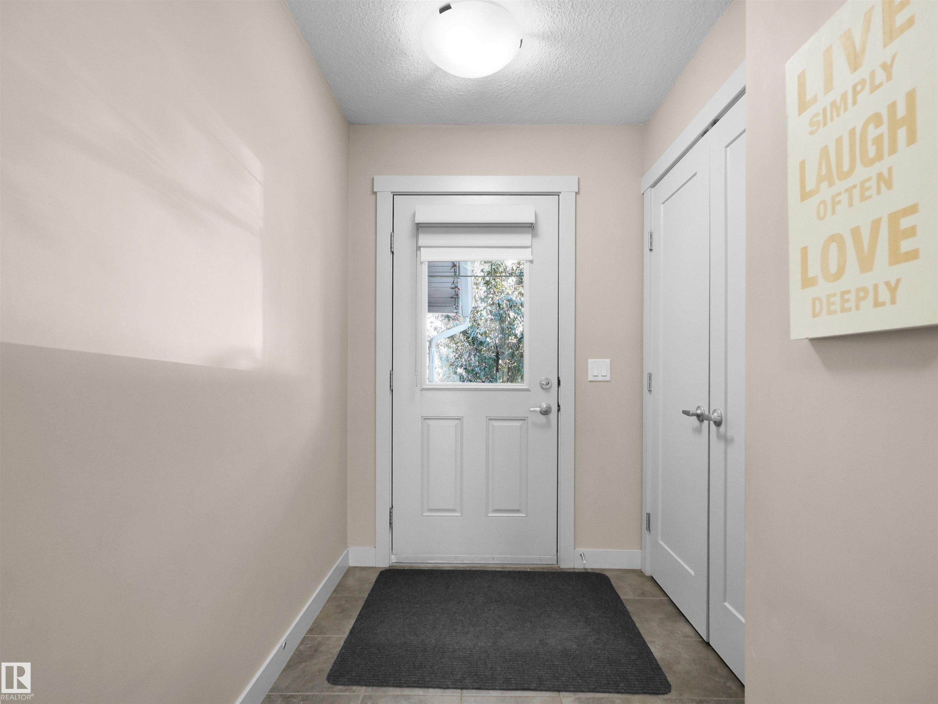 Entryway featuring a white door with a window, white trim, neutral-toned walls, and tile flooring - 4487 Annett Common Sw, Edmonton, AB - Indoor Photo Showing Other Room