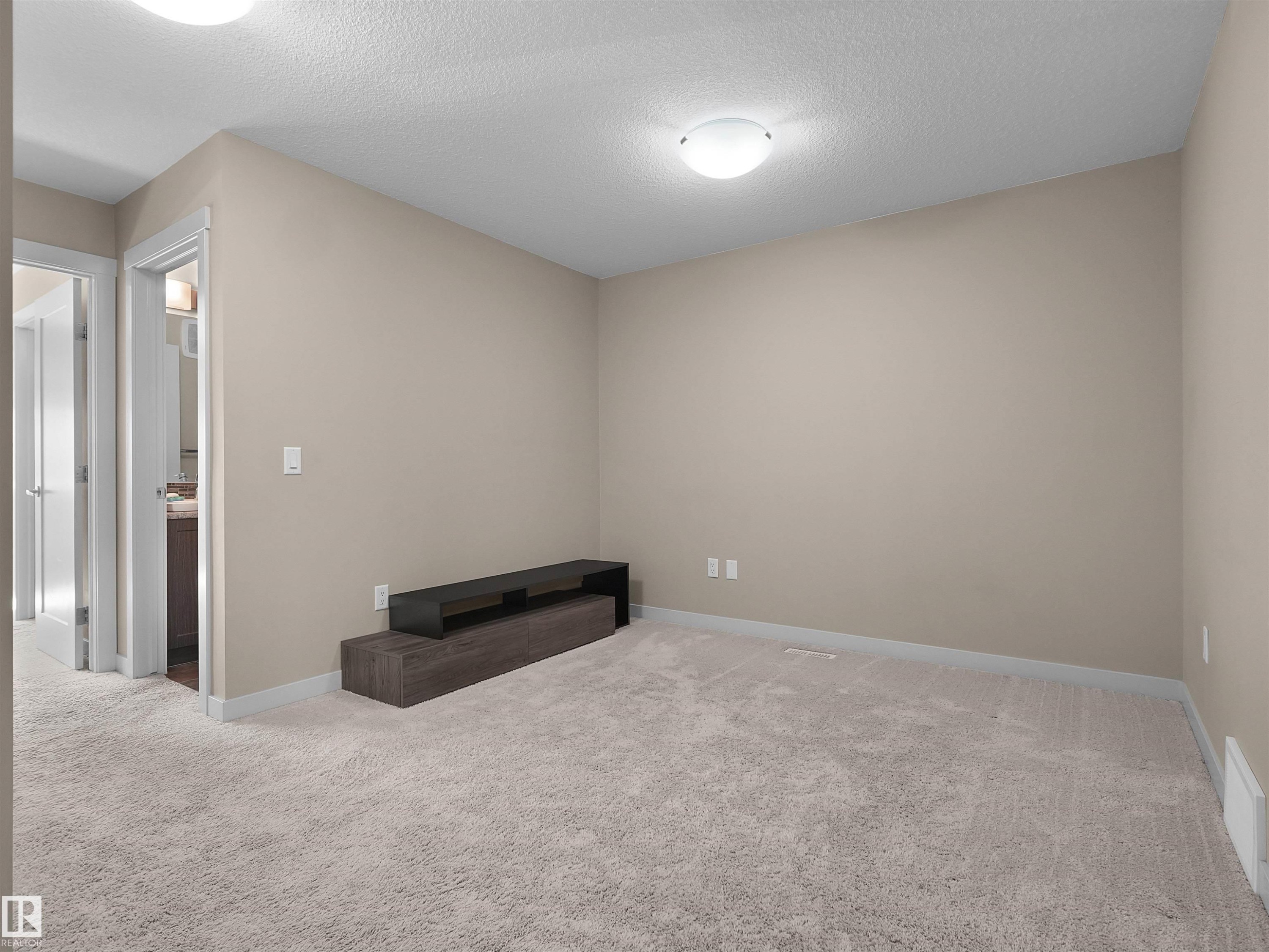 Plush gray carpeting extends throughout this room, featuring neutral beige walls and white trim - 4487 Annett Common Sw, Edmonton, AB - Indoor Photo Showing Other Room