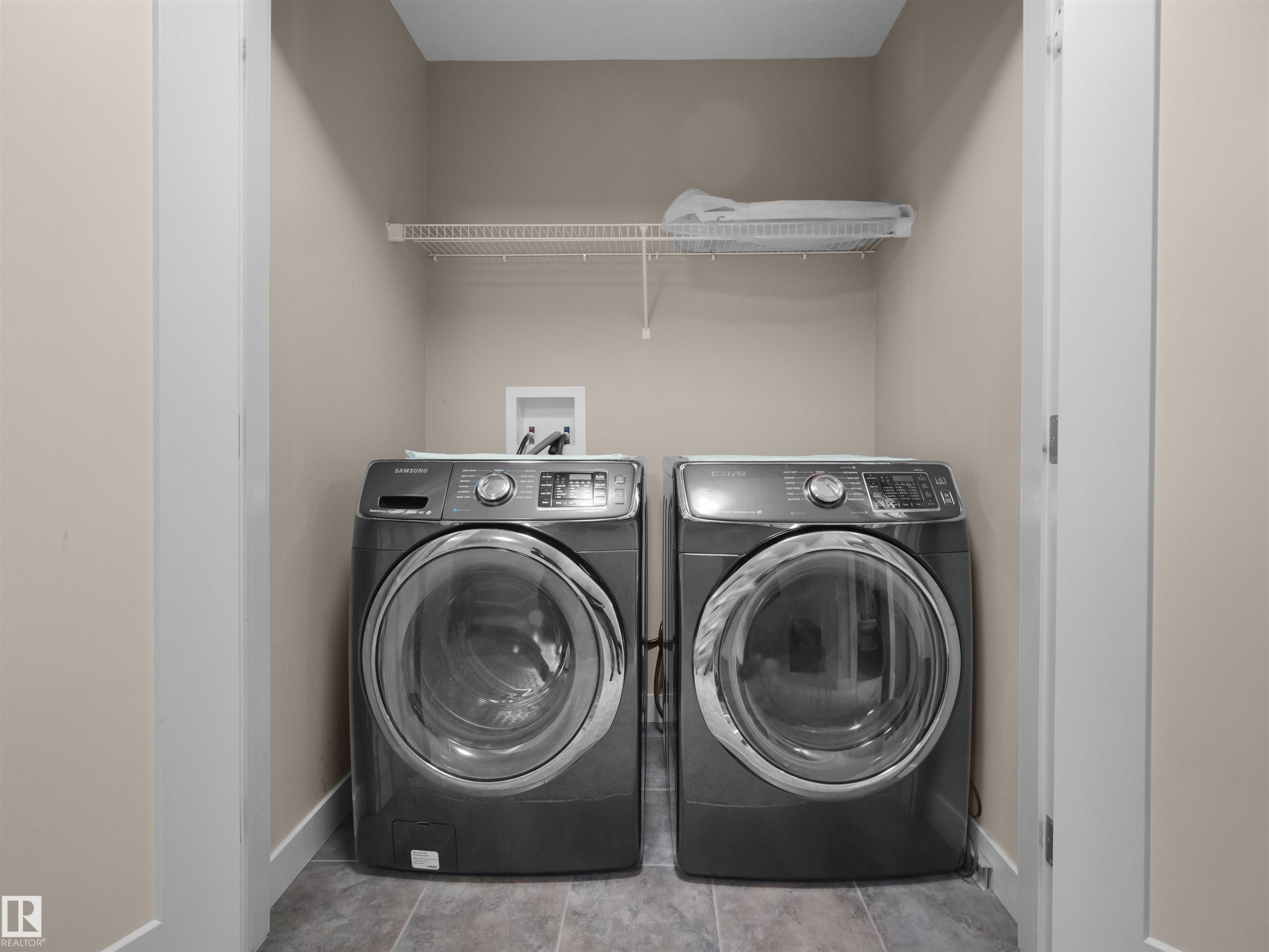 Dedicated laundry alcove featuring neutral-toned walls, tile flooring, and a white wire shelf - 4487 Annett Common Sw, Edmonton, AB - Indoor Photo Showing Laundry Room