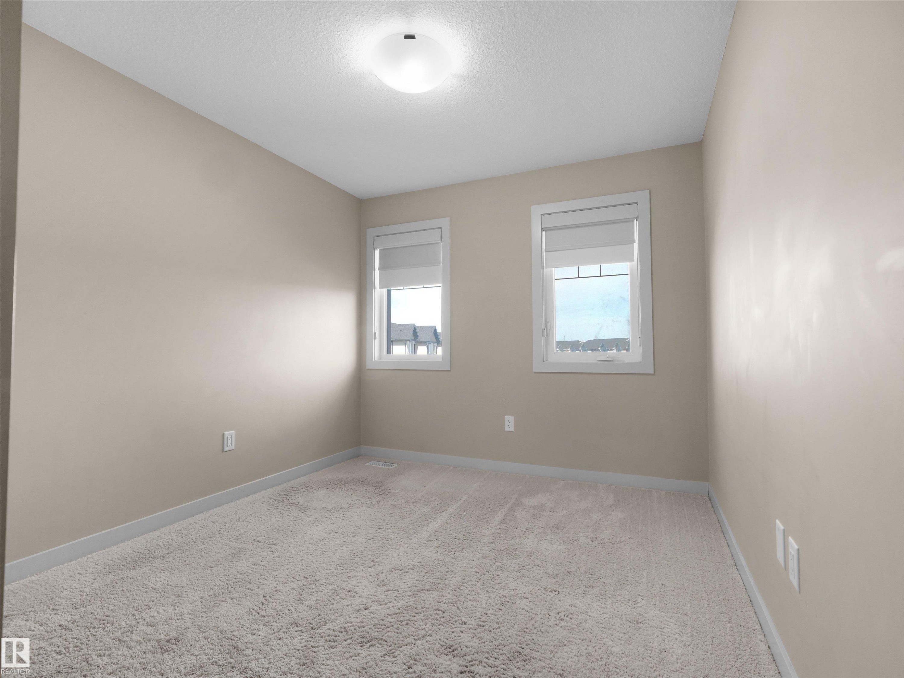Neutral-toned room featuring a soft carpeted floor and two windows with blinds - 4487 Annett Common Sw, Edmonton, AB - Indoor Photo Showing Other Room