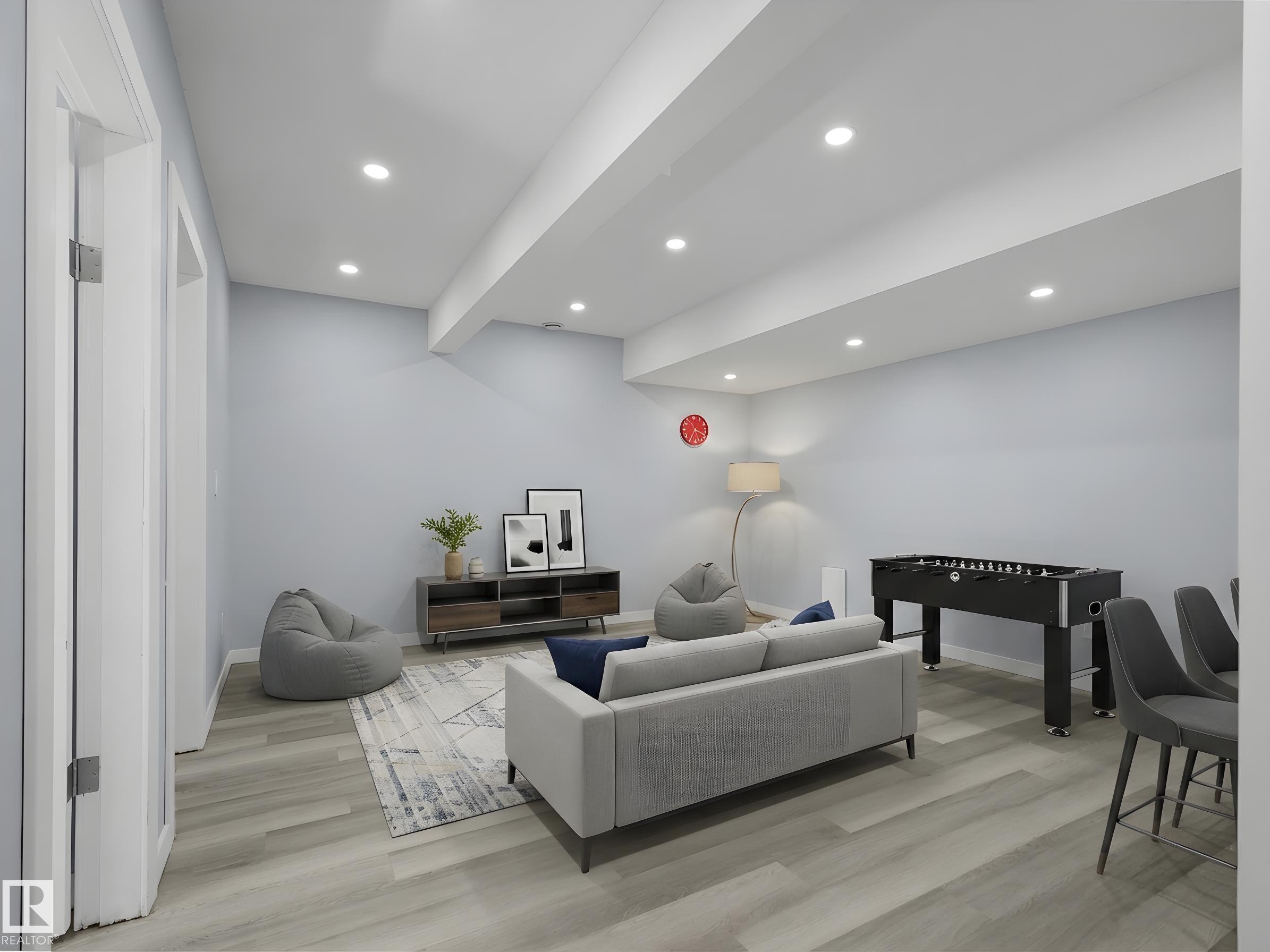 Recessed lighting illuminates this expansive recreation area featuring wood-finish flooring, light blue walls, and white trim - 4487 Annett Common Sw, Edmonton, AB - Indoor