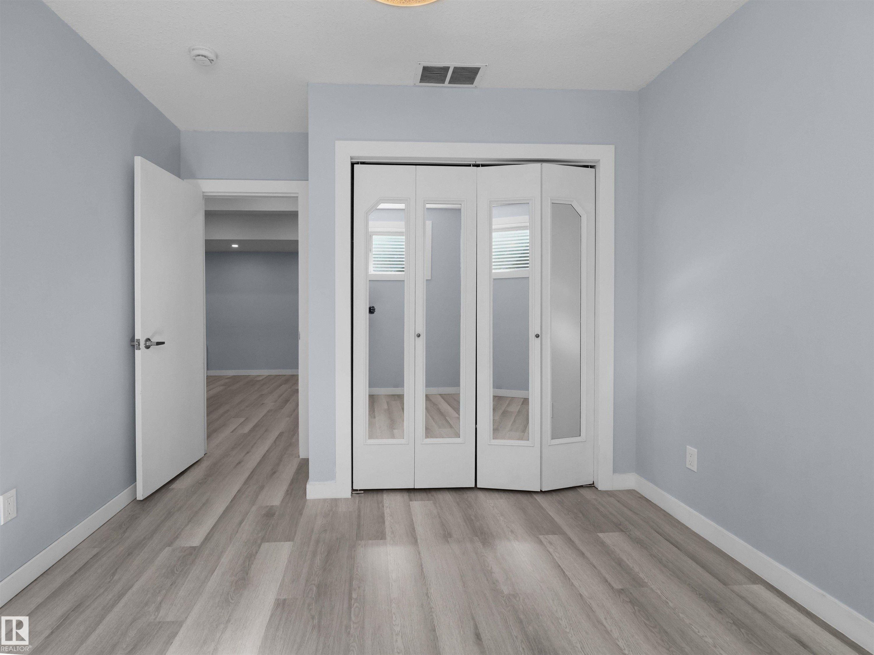 Light gray wood-finish flooring complements soft blue-gray walls - 4487 Annett Common Sw, Edmonton, AB - Indoor Photo Showing Other Room