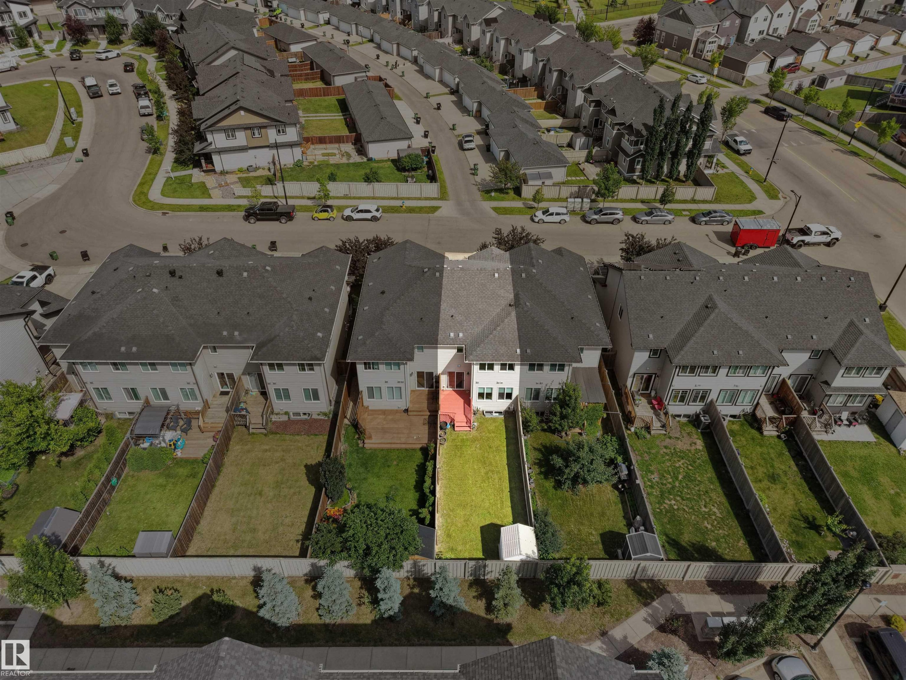 Backyard with fenced perimeter, green lawn, mature trees, and a small storage shed - 4487 Annett Common Sw, Edmonton, AB - With View