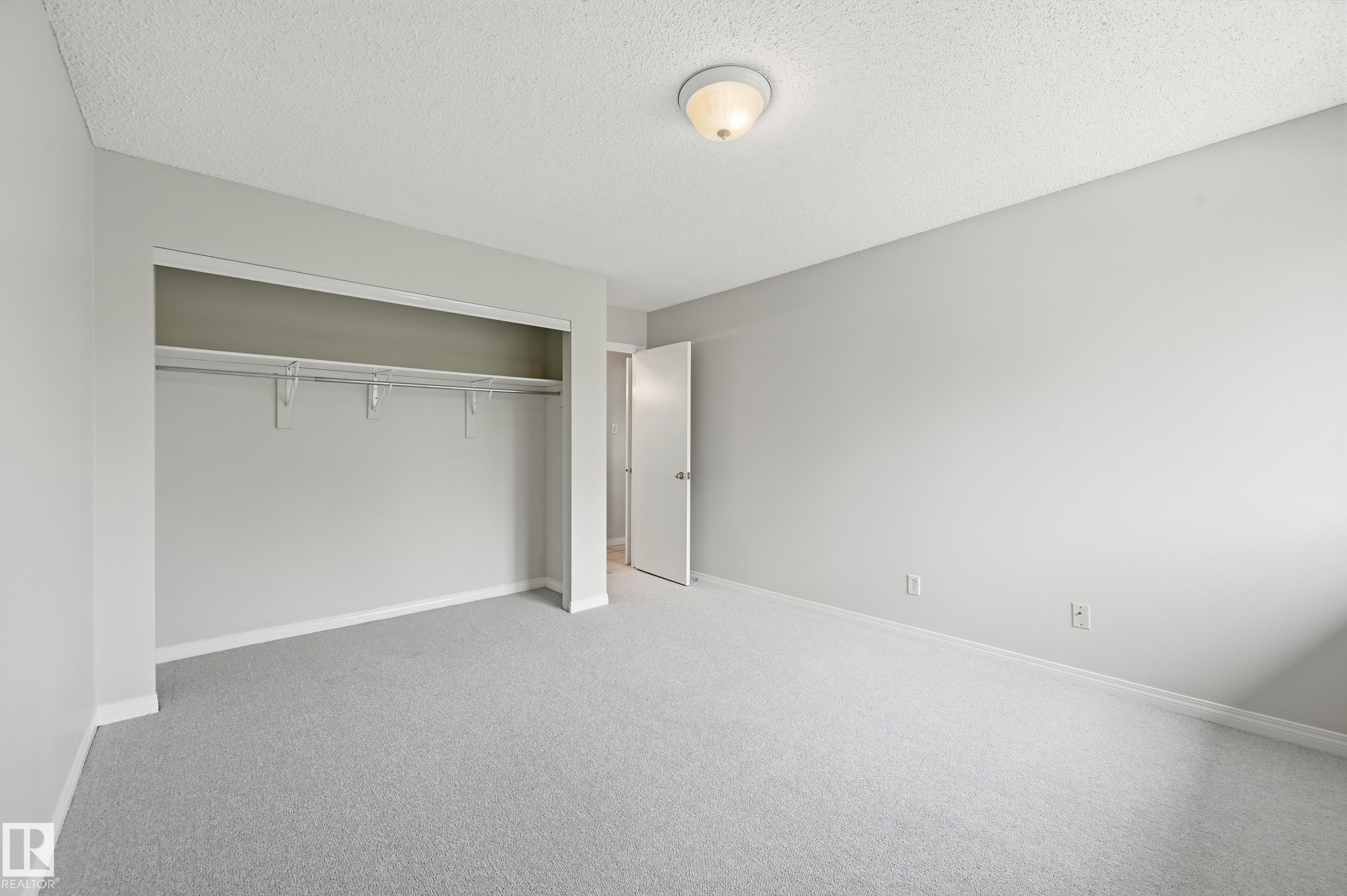 Bedroom featuring light grey carpeting, white baseboards, and a neutral wall color - #433 11217 103 Av Nw, Edmonton, AB - Indoor Photo Showing Other Room
