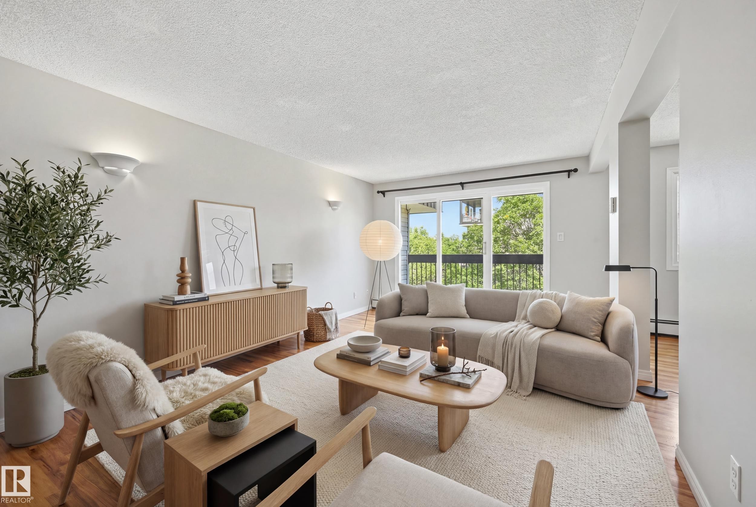 Living area featuring wood-finish flooring, a neutral color palette, and multiple wall sconces - #433 11217 103 Av Nw, Edmonton, AB - Indoor Photo Showing Living Room