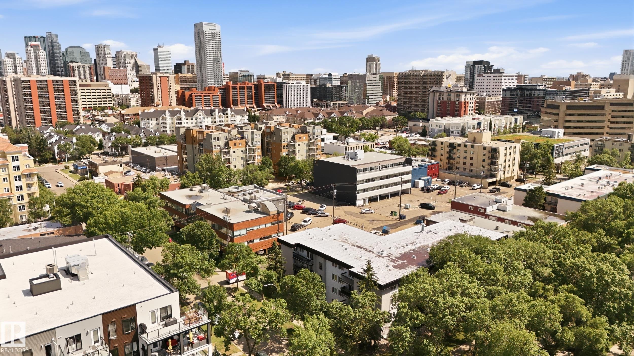 Urban landscape featuring a diverse architectural mix, mature tree canopy, and distant high-rise structures - #433 11217 103 Av Nw, Edmonton, AB - Outdoor With View