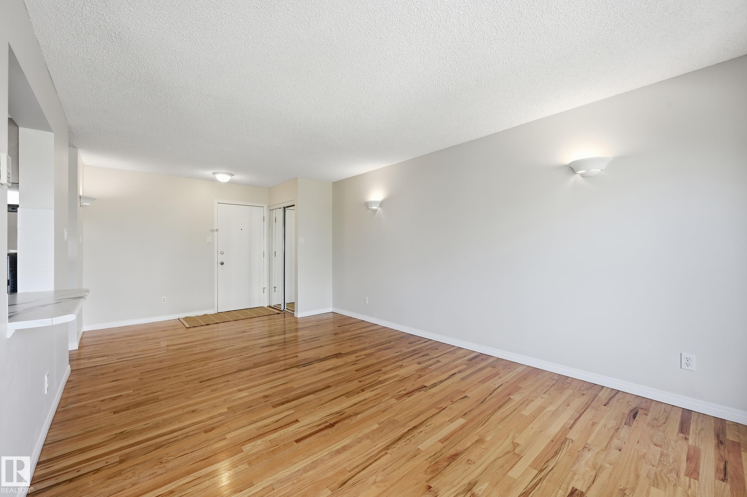 Spacious room with wood-finish flooring, white baseboards, and neutral wall paint - #433 11217 103 Av Nw, Edmonton, AB - Indoor Photo Showing Other Room