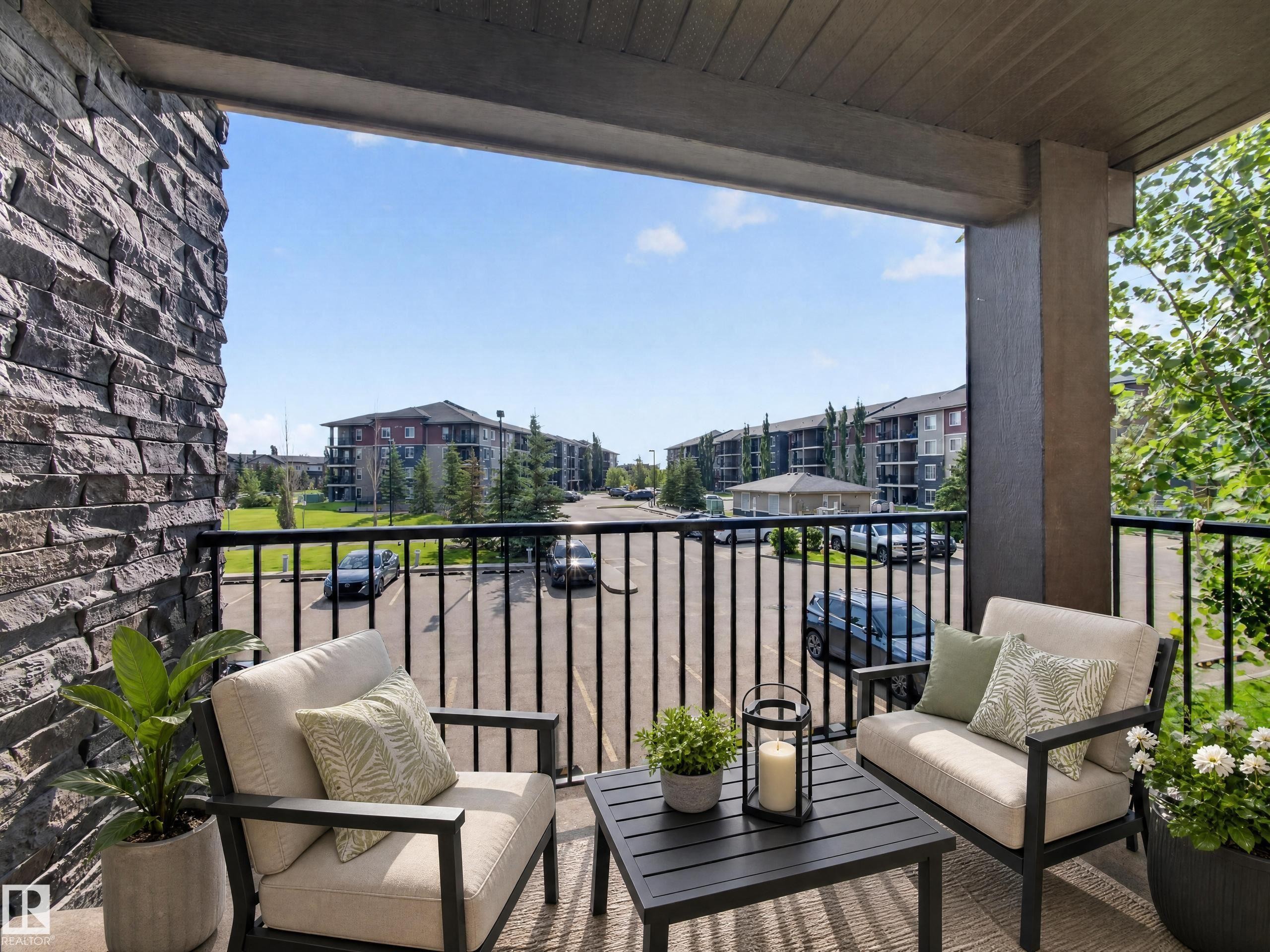 Private balcony featuring a black metal railing and a stone-clad exterior wall - #217 12045 22 Av Sw, Edmonton, AB - Outdoor With Deck Patio Veranda With Exterior