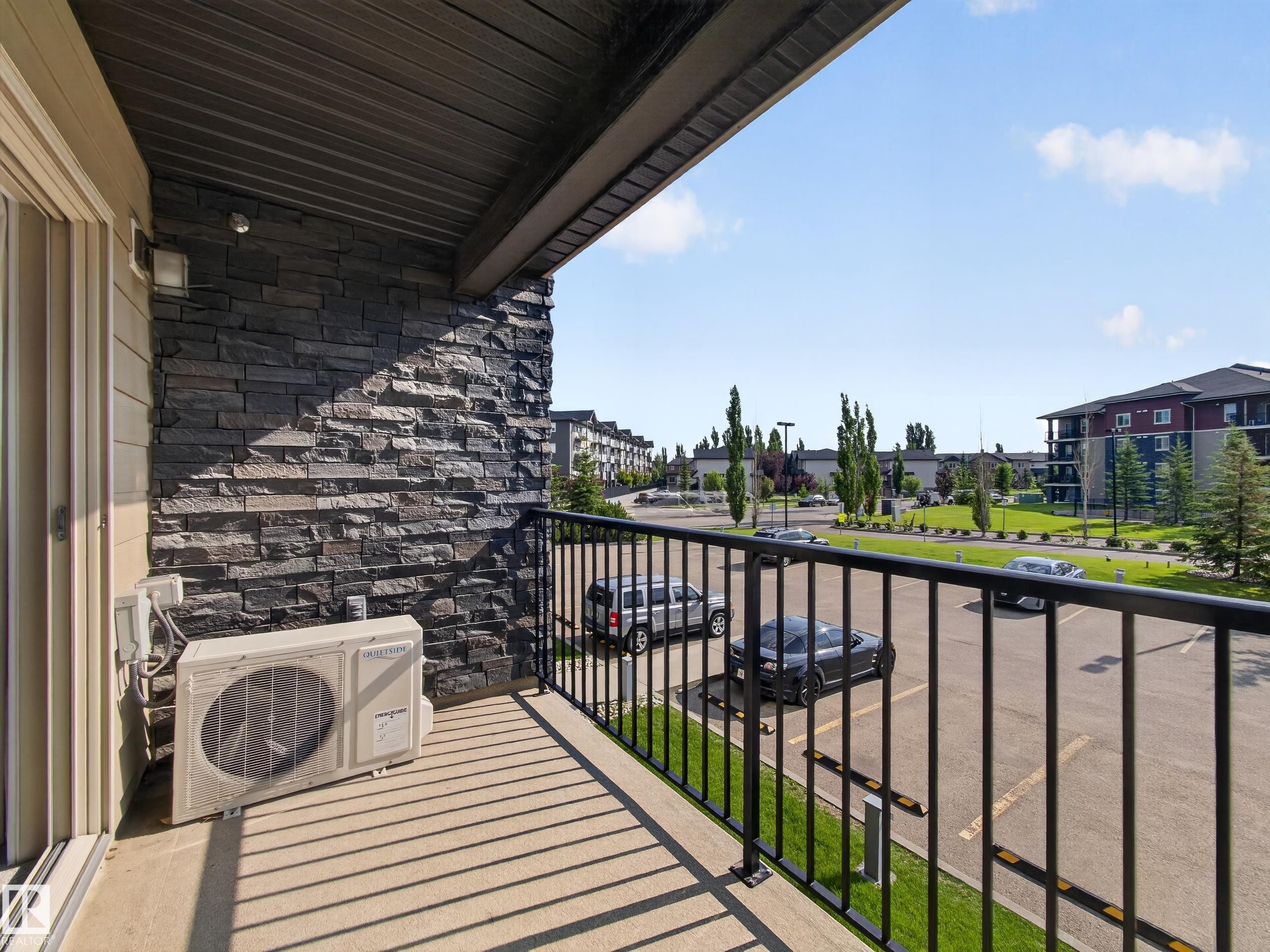 Outdoor balcony featuring a black metal railing and a stone accent wall - #217 12045 22 Av Sw, Edmonton, AB - Outdoor With Balcony With Exterior