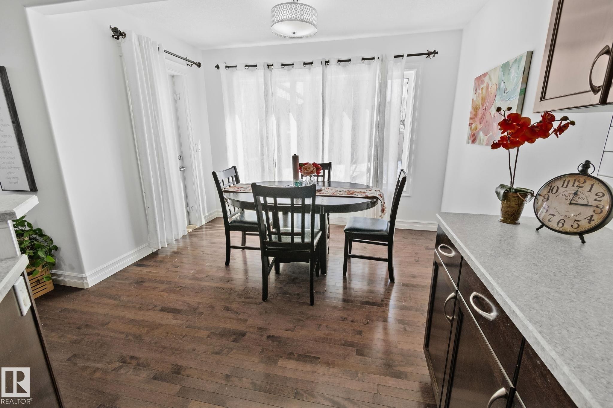 This dining area features hardwood floors and a contemporary ceiling light fixture - 1115 61 Street Sw, Edmonton, AB