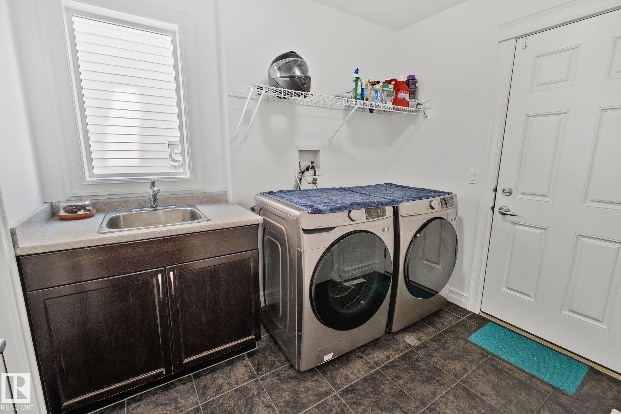 The property features a dedicated laundry area with durable floor tiling and a window for natural light - 1115 61 Street Sw, Edmonton, AB
