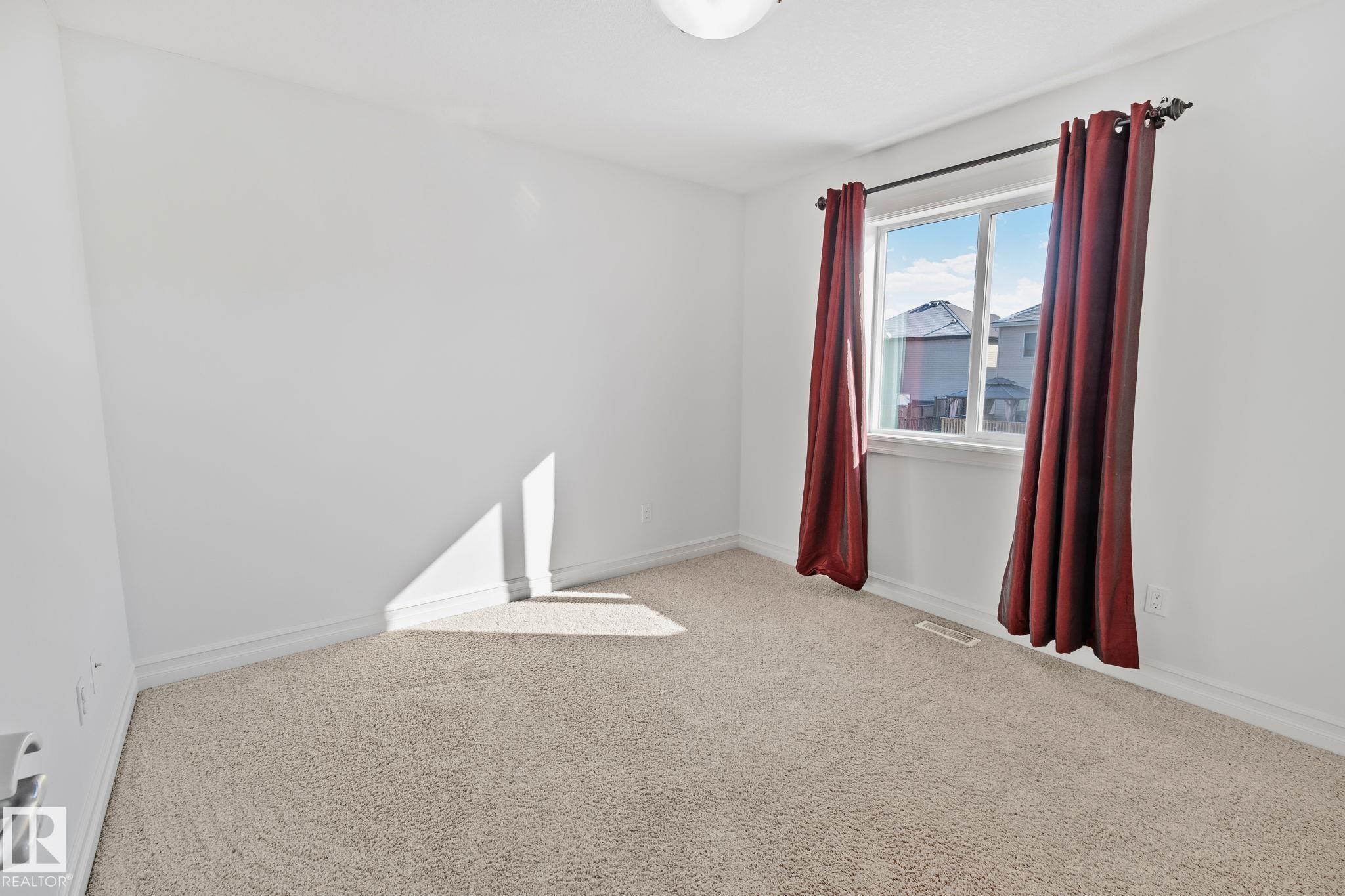 This room features light-colored carpeting, white walls, and a window providing natural light - 1115 61 Street Sw, Edmonton, AB