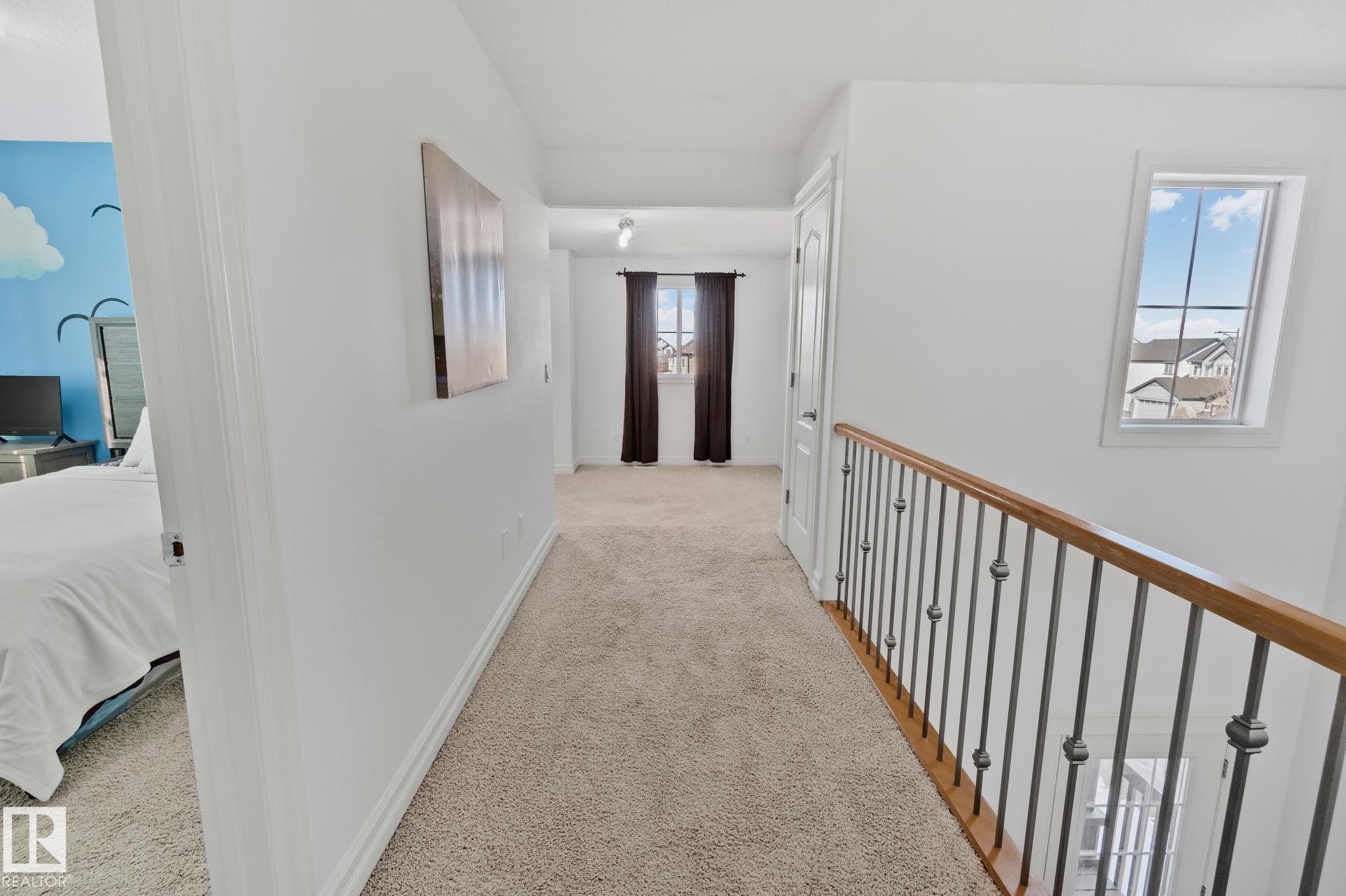 The property features a hallway with carpeted flooring, white walls, and a window providing natural light - 1115 61 Street Sw, Edmonton, AB