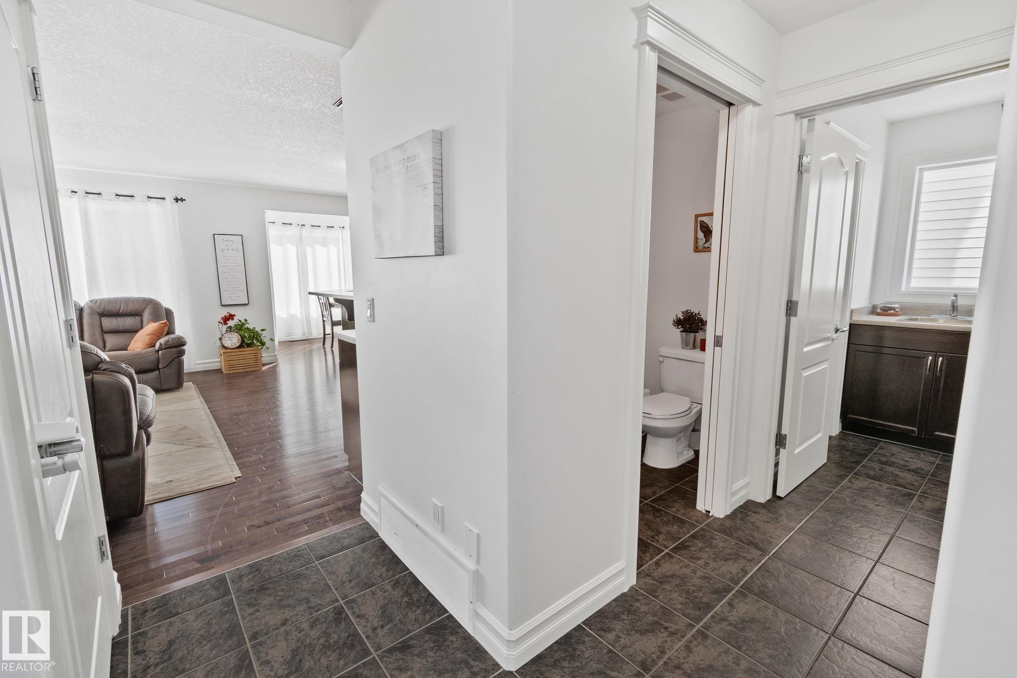 View of the main floor featuring tiled flooring, a powder room with a toilet, and another bathroom with a vanity and sink - 1115 61 Street Sw, Edmonton, AB