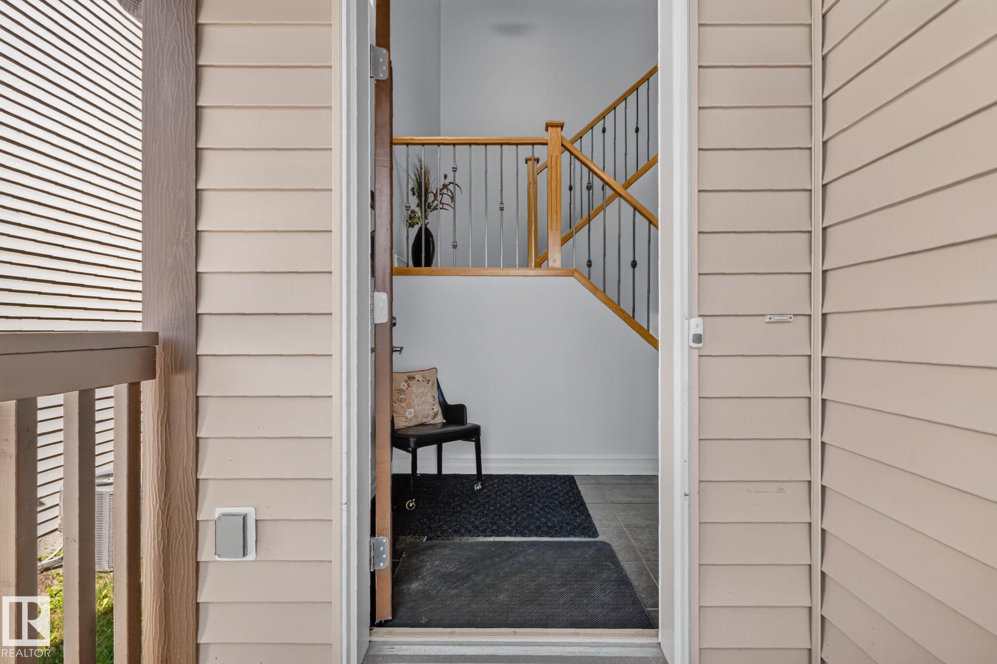 Light-colored siding exterior with a wood-finish porch railing - 1115 61 Street Sw, Edmonton, AB