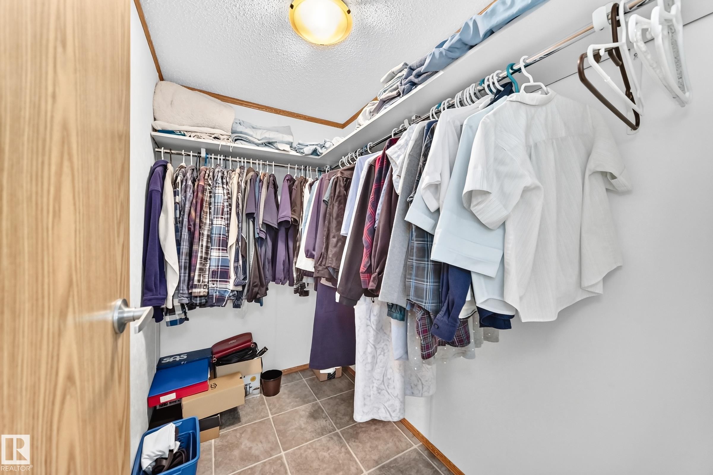 Walk-in closet featuring an overhead light fixture, multiple upper storage shelves, and ample hanging rod space - #225 3400 48 St, Stony Plain, AB - Indoor With Storage