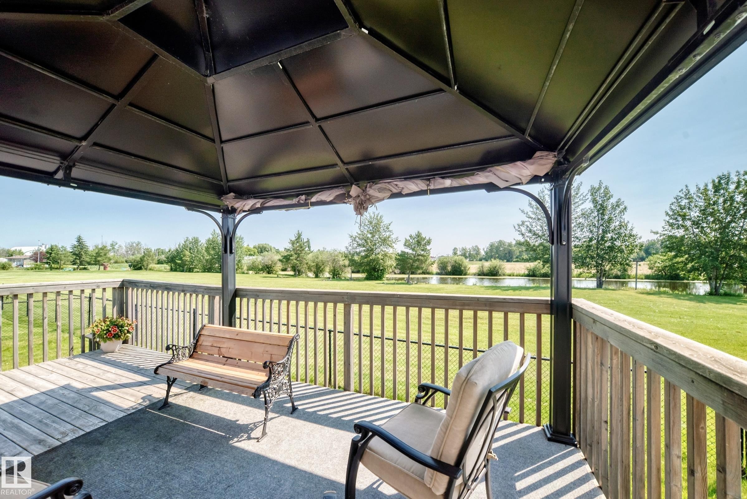 Outdoor gazebo with a black metal frame, a solid roof, and a wood-finish deck - #225 3400 48 St, Stony Plain, AB - Outdoor With Deck Patio Veranda With Exterior