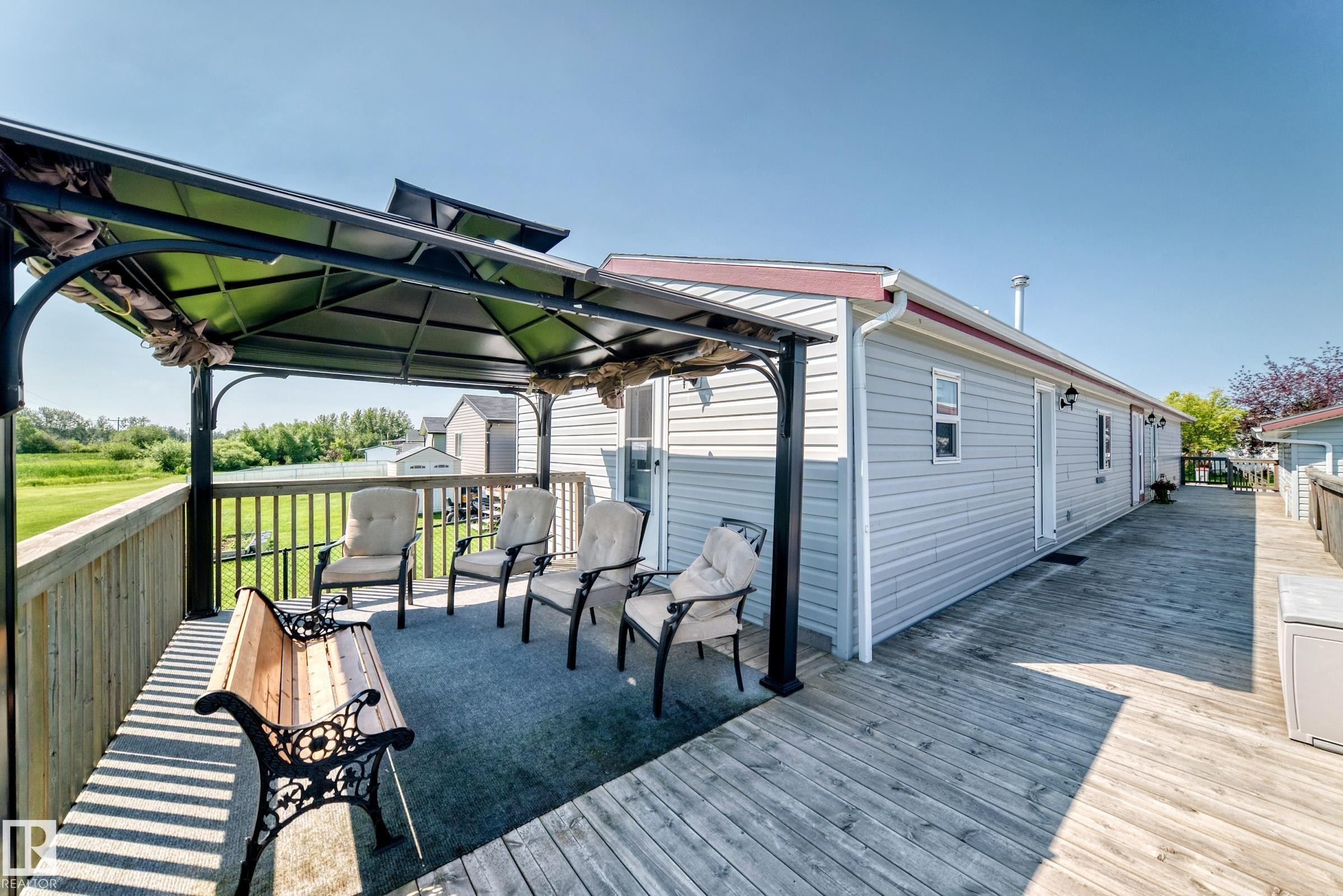 Expansive wood deck with a built-in gazebo featuring a dark metal frame and fabric canopy - #225 3400 48 St, Stony Plain, AB - Outdoor With Deck Patio Veranda With Exterior