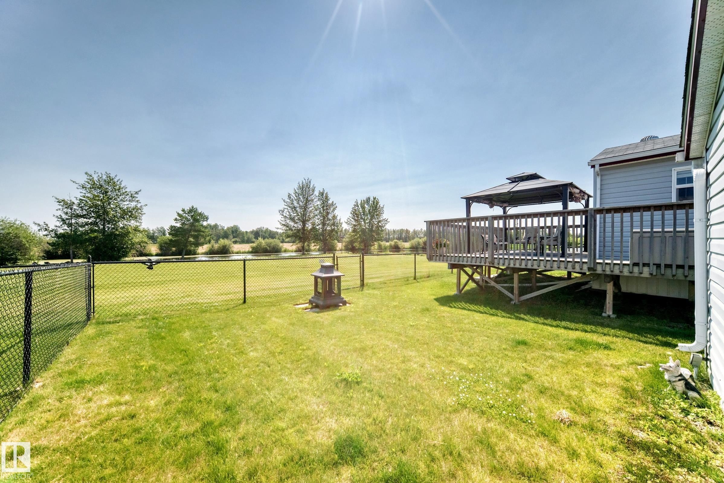 Expansive backyard featuring a manicured lawn, full perimeter fencing, and a raised wooden deck with a gazebo - #225 3400 48 St, Stony Plain, AB - Outdoor With Deck Patio Veranda