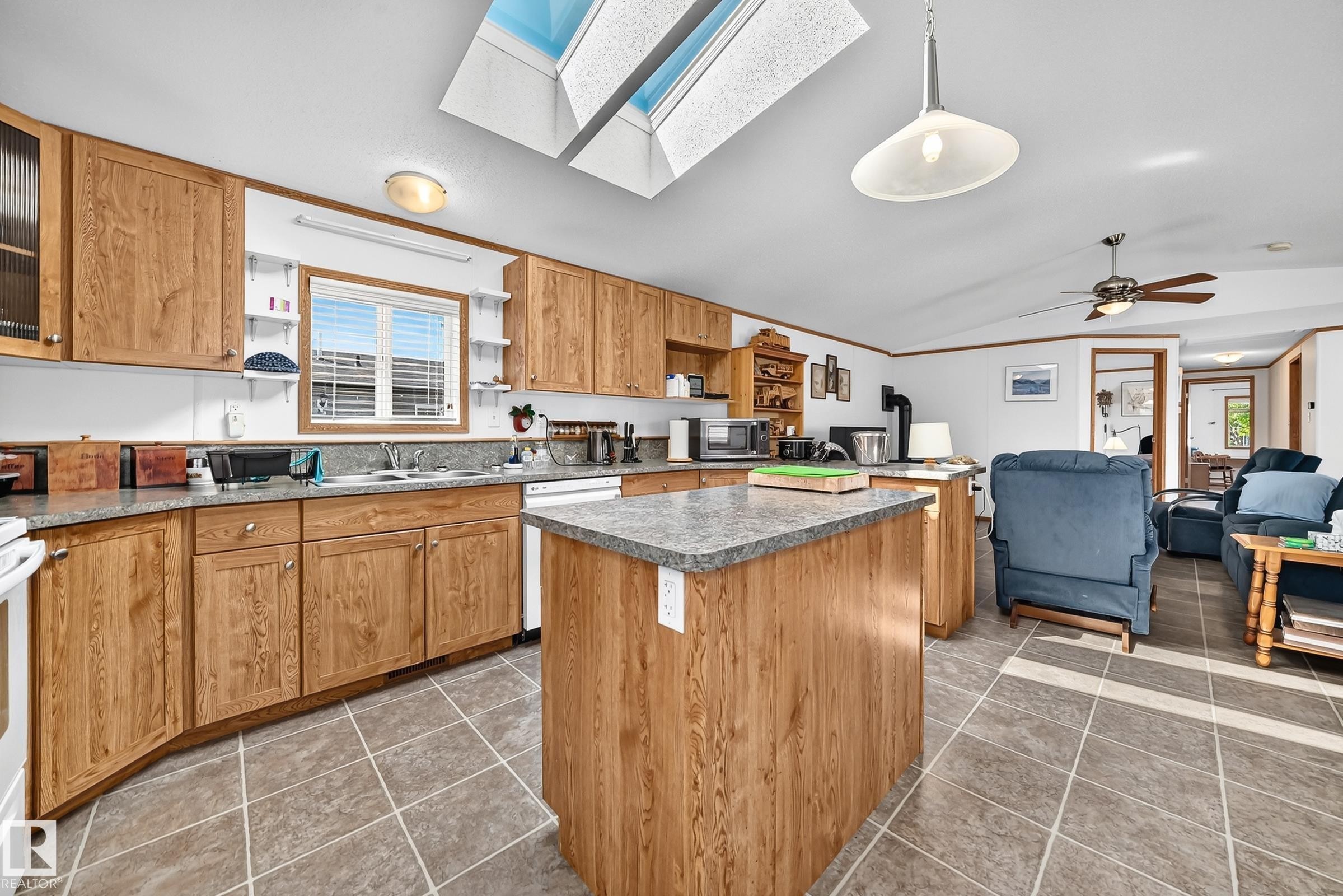 Kitchen featuring wood-finish cabinetry, a central island with countertop, and a double basin sink - #225 3400 48 St, Stony Plain, AB - Indoor Photo Showing Kitchen With Double Sink