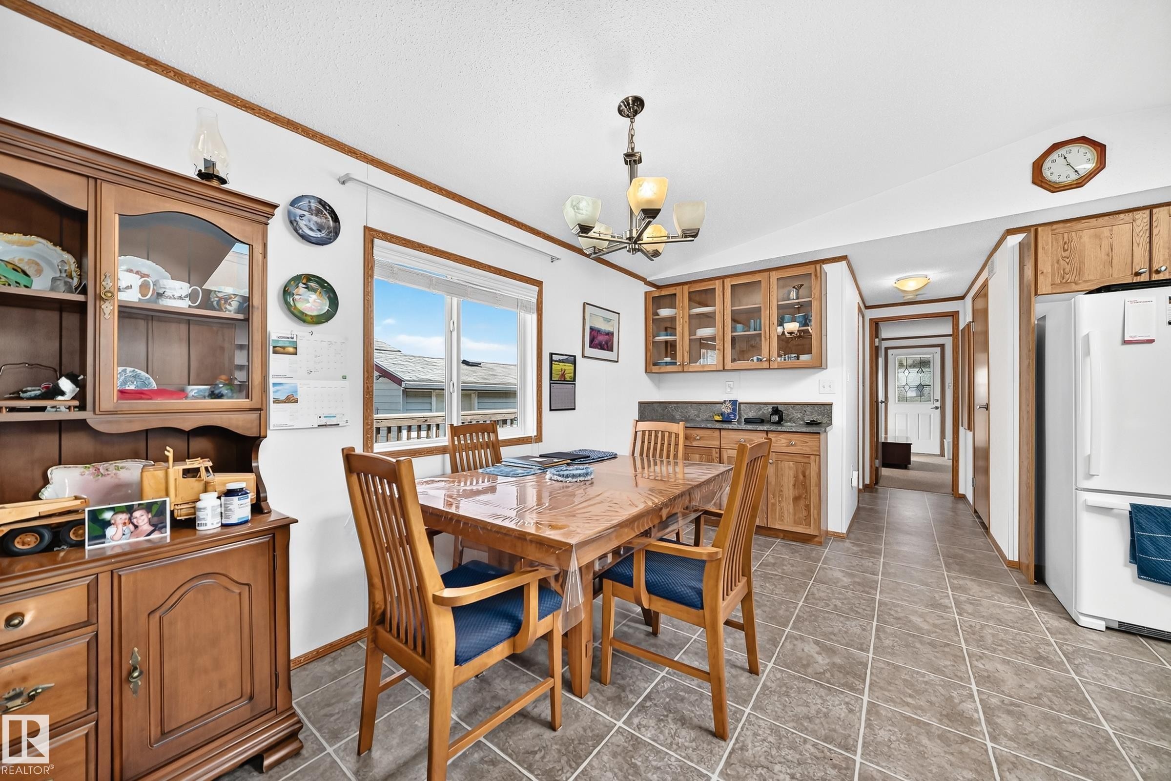 Dining area featuring tile flooring, a window providing natural light, a ceiling-mounted light fixture, and wood-finish cabinetry - #225 3400 48 St, Stony Plain, AB - Indoor Photo Showing Dining Room