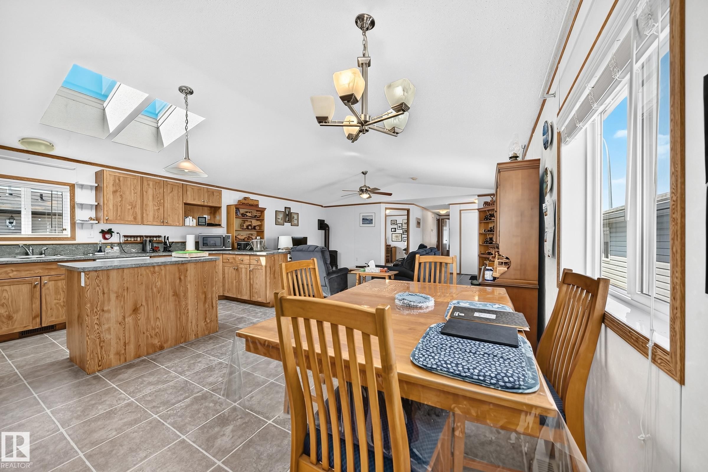 Kitchen featuring wood-finish cabinetry, a central island with countertop, and two skylights - #225 3400 48 St, Stony Plain, AB - Indoor Photo Showing Dining Room