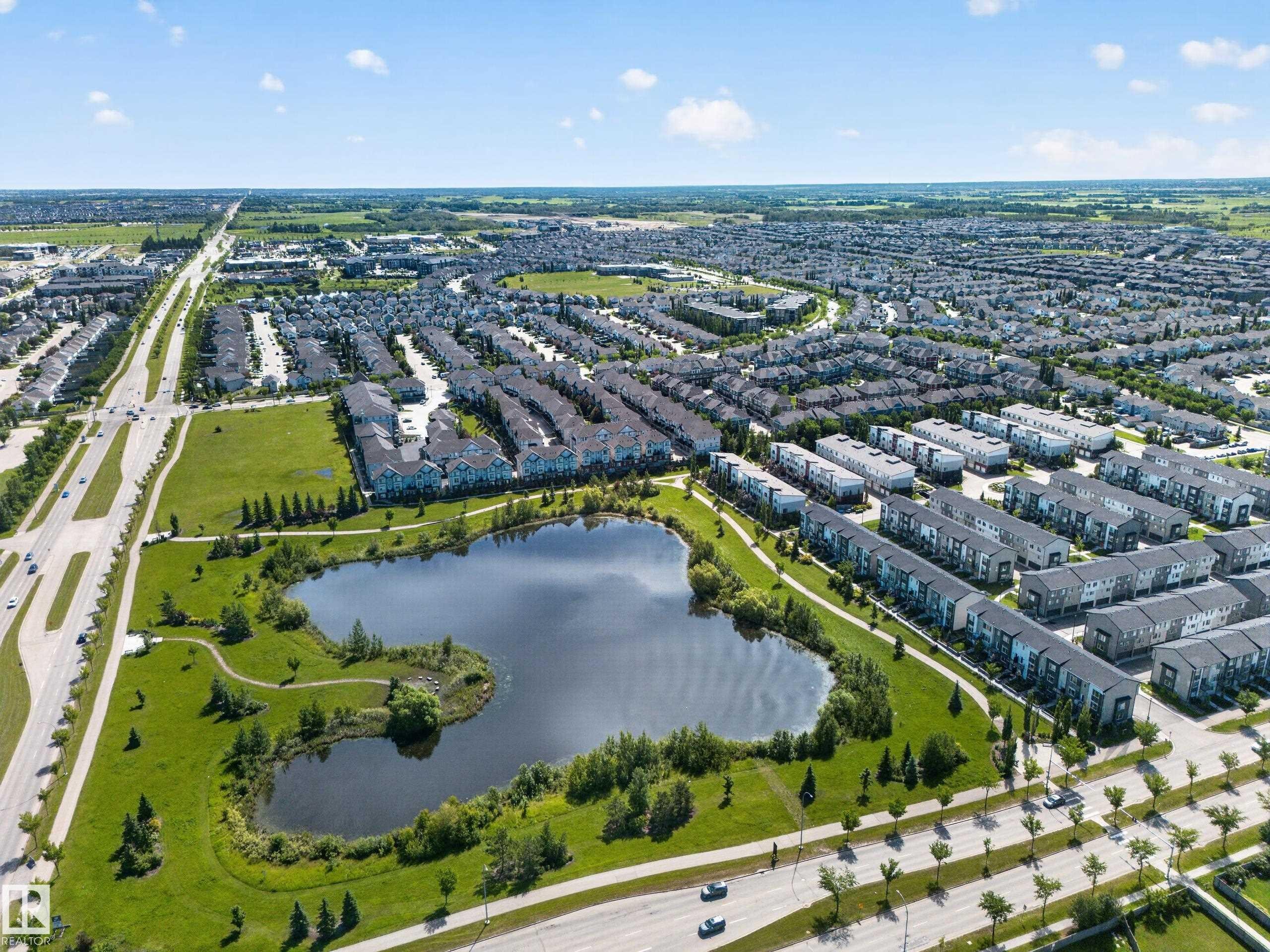 Aerial perspective showcasing a developed residential area with extensive green spaces - #100 804 Welsh Dr Sw, Edmonton, AB - Outdoor With Body Of Water With View