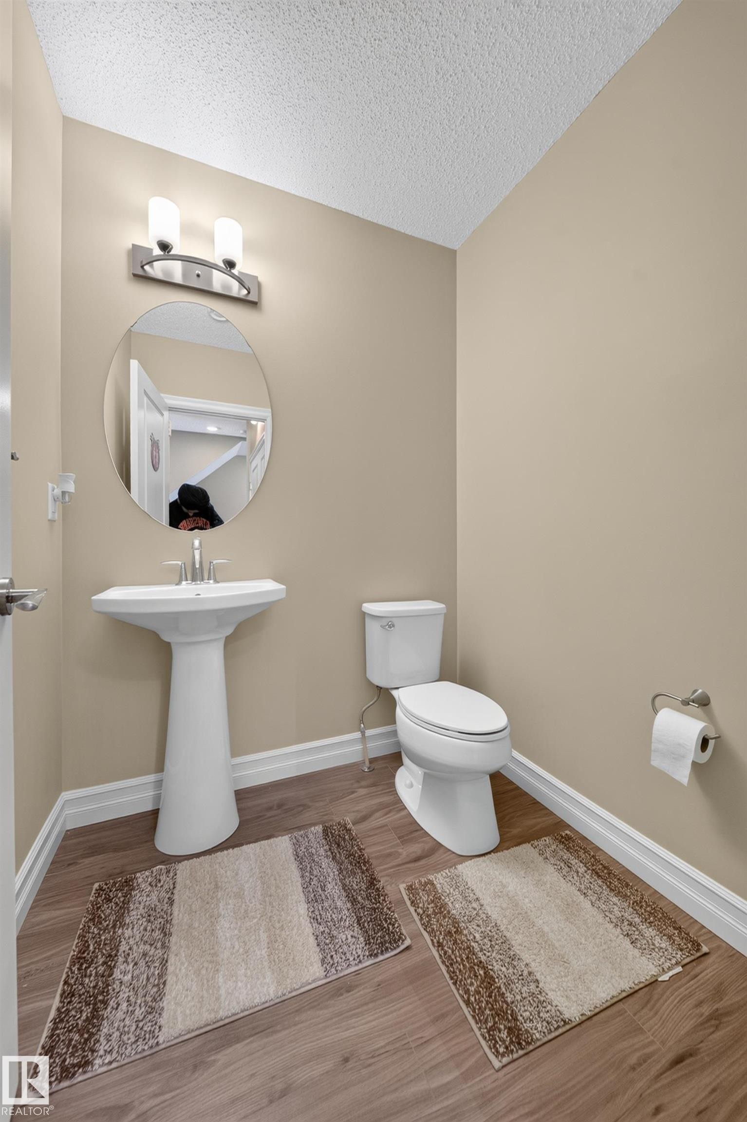 Pedestal sink and toilet with wood-finish flooring - #100 804 Welsh Dr Sw, Edmonton, AB - Indoor Photo Showing Bathroom