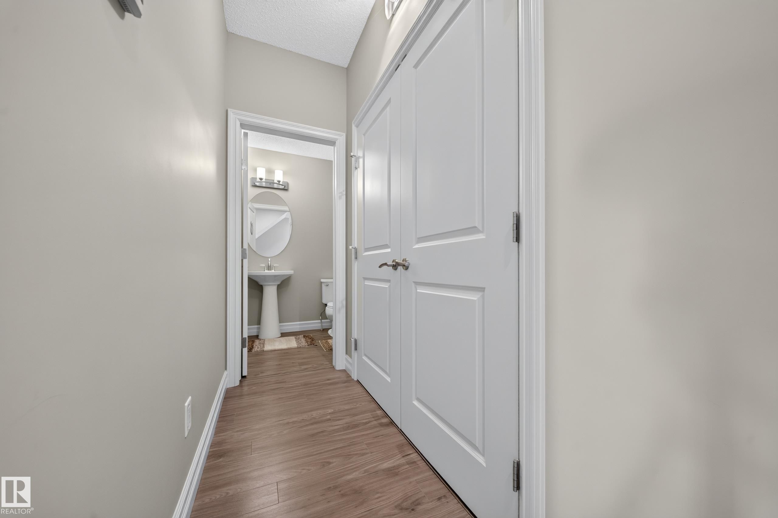 Hallway featuring wood-finish flooring, light grey walls, and white paneled doors - #100 804 Welsh Dr Sw, Edmonton, AB - Indoor Photo Showing Other Room