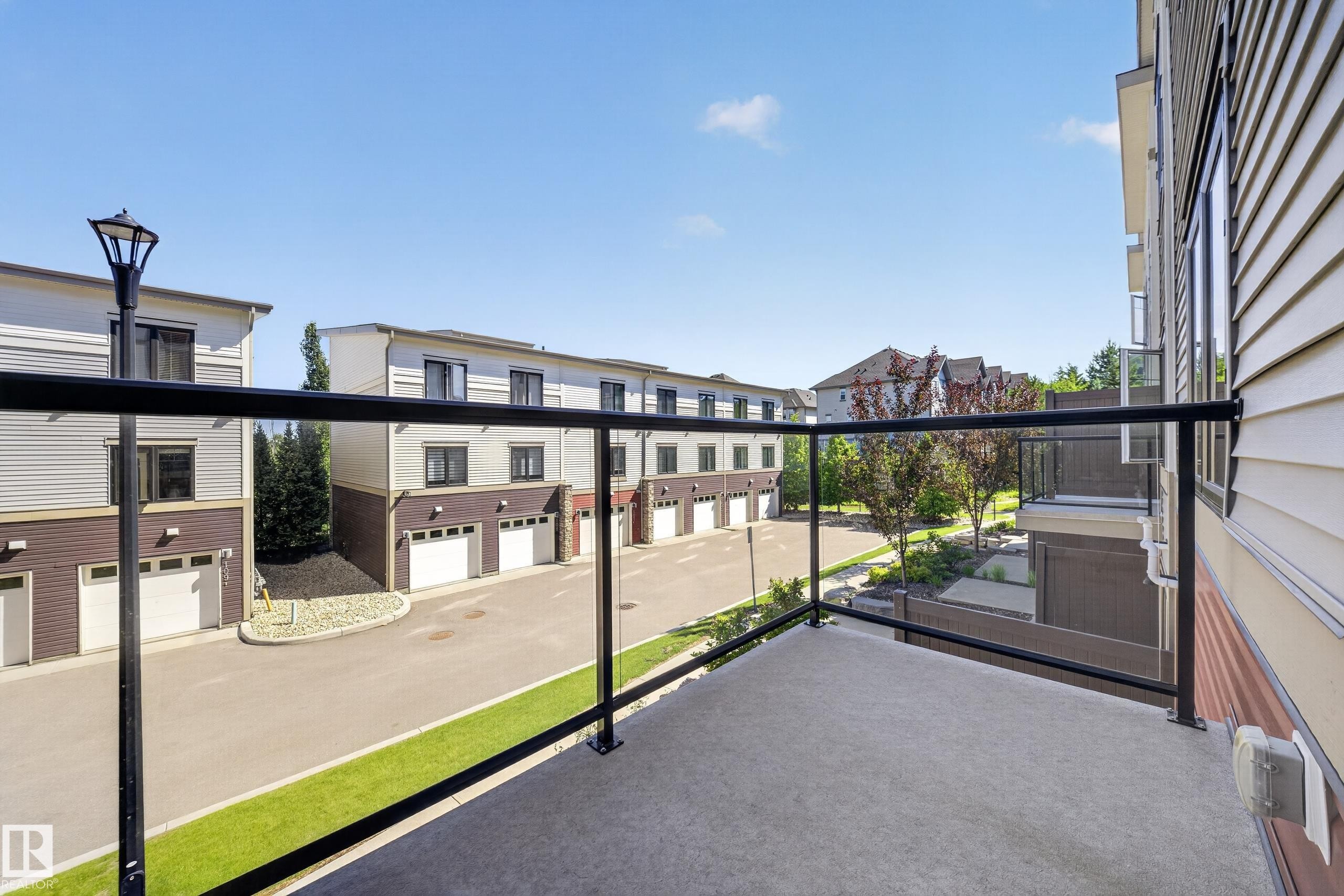 Balcony featuring a glass railing and concrete flooring - #100 804 Welsh Dr Sw, Edmonton, AB - Outdoor With Balcony With Exterior