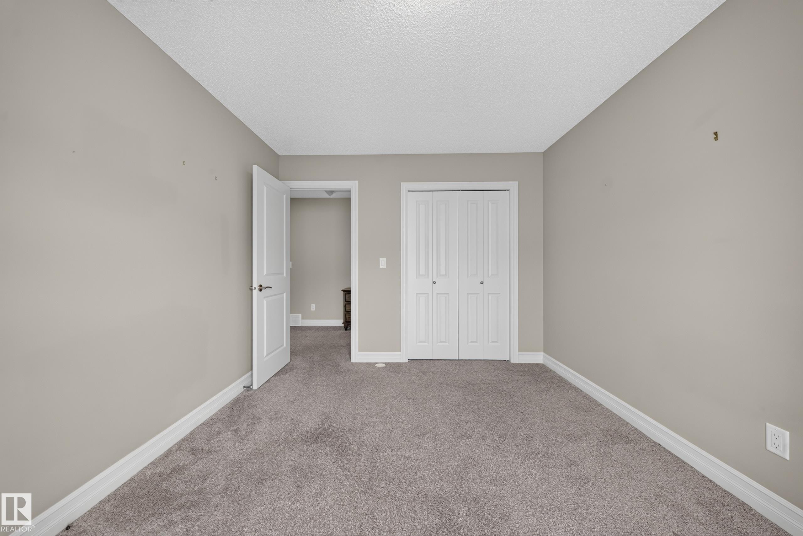 Carpeted interior room with neutral-toned walls, white baseboards, and a white ceiling - #100 804 Welsh Dr Sw, Edmonton, AB - Indoor Photo Showing Other Room