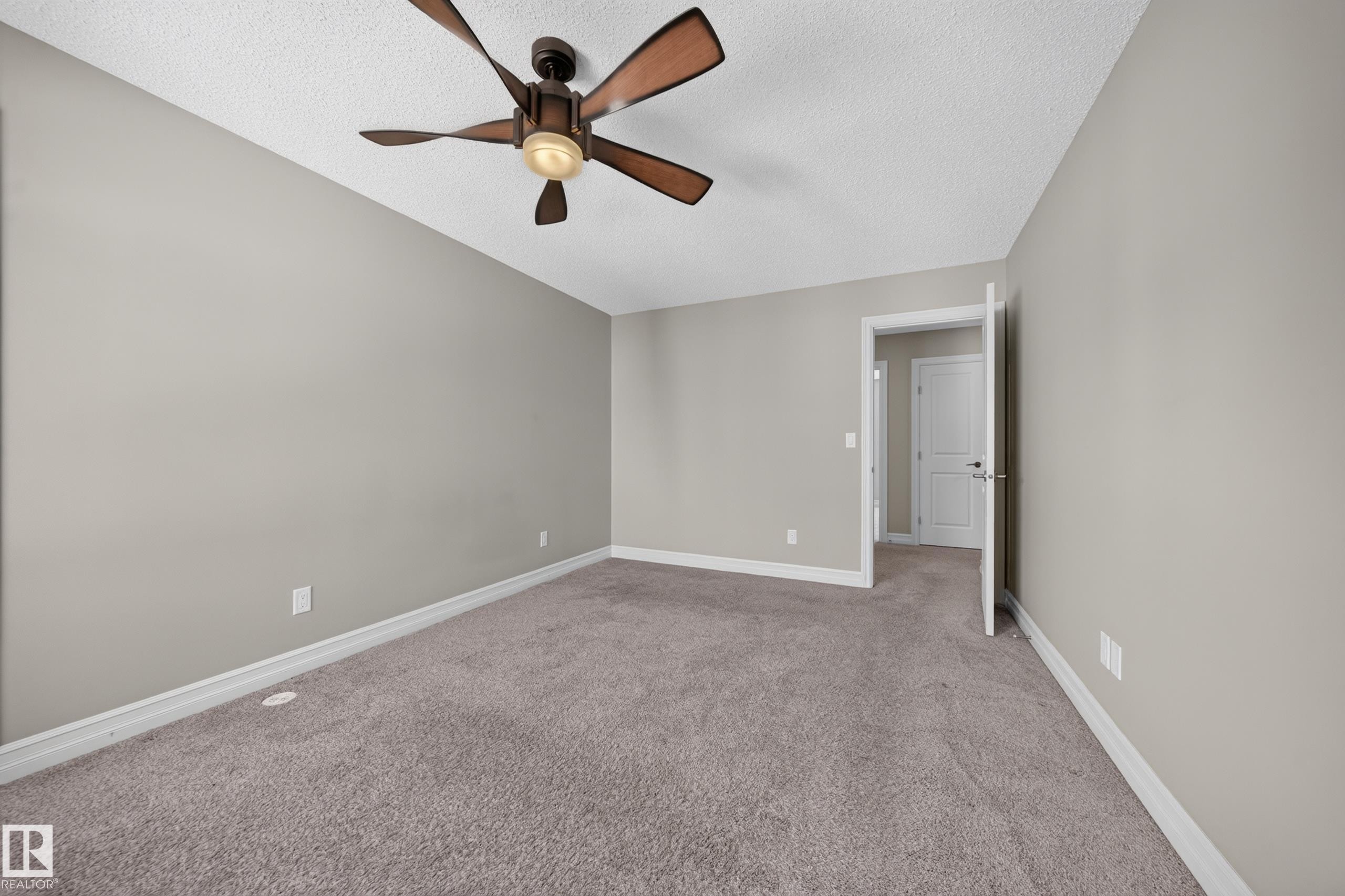 Spacious room featuring neutral paint tones, plush carpeting, a multi-blade ceiling fan with integrated lighting, and white baseboards - #100 804 Welsh Dr Sw, Edmonton, AB - Indoor Photo Showing Other Room