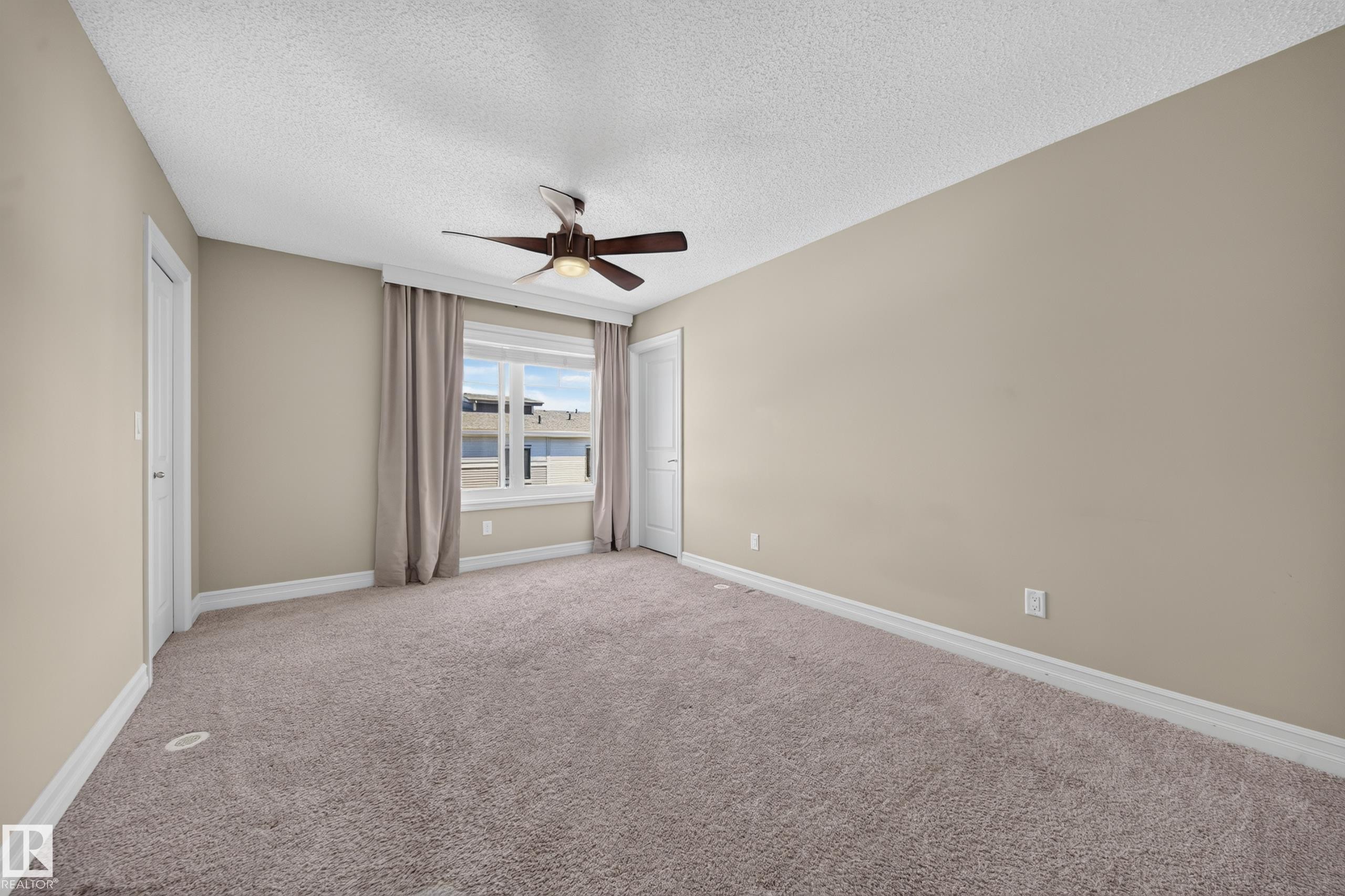 Spacious room featuring neutral carpeting, light beige wall paint, and white trim - #100 804 Welsh Dr Sw, Edmonton, AB - Indoor Photo Showing Other Room