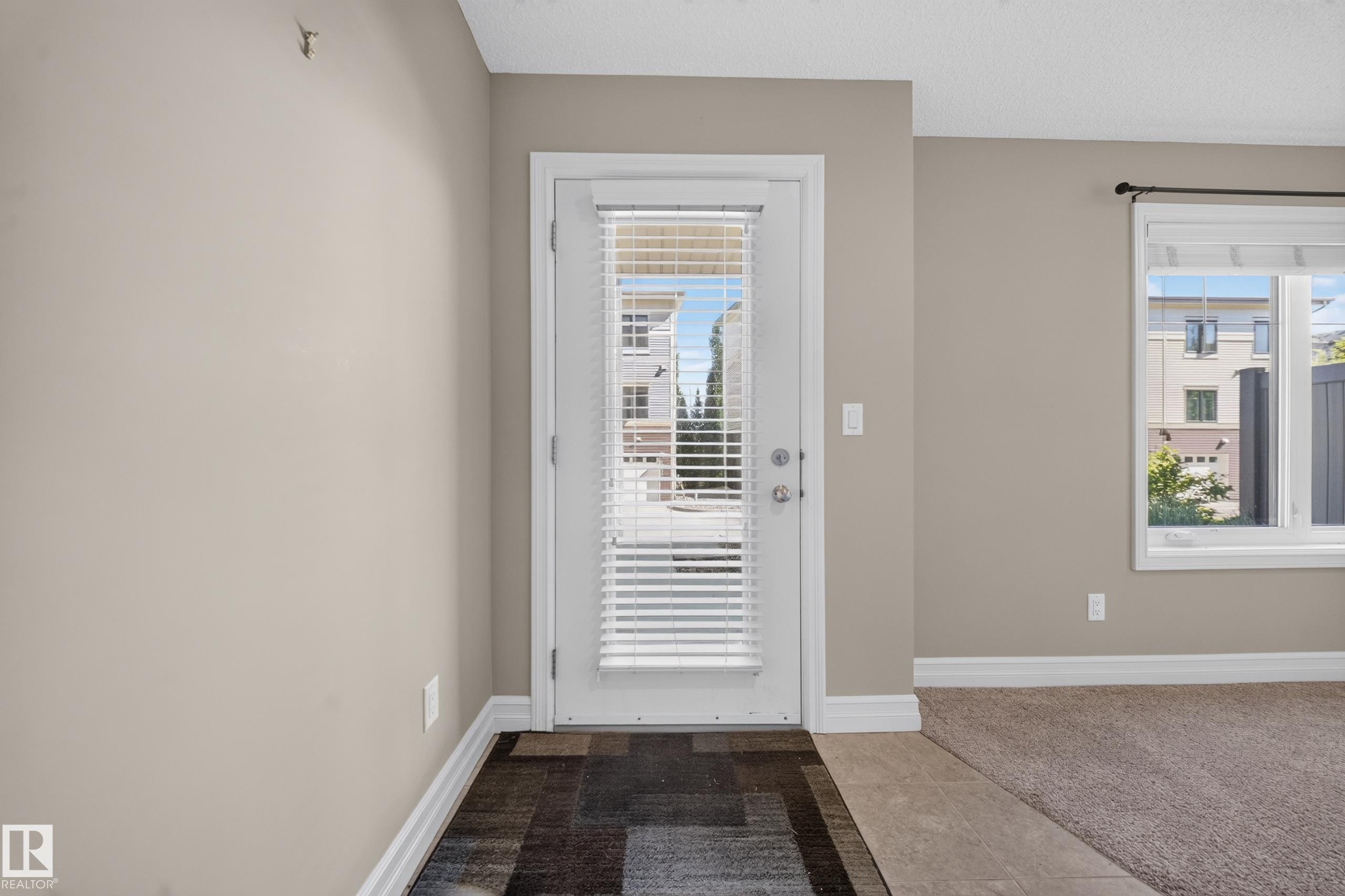 Entryway with a full-light door featuring internal blinds, wood-finish flooring, and light neutral wall tones - #100 804 Welsh Dr Sw, Edmonton, AB - Indoor Photo Showing Other Room