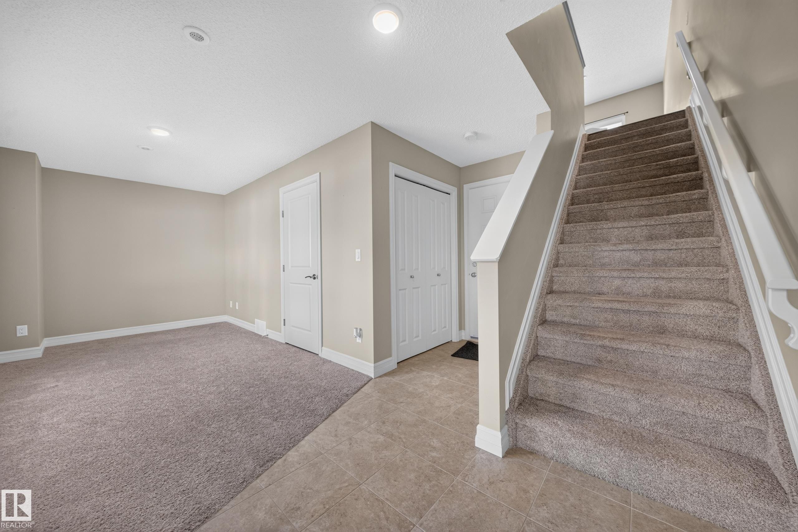 Carpeted staircase with white railings, tile flooring, and neutral wall tones - #100 804 Welsh Dr Sw, Edmonton, AB - Indoor Photo Showing Other Room