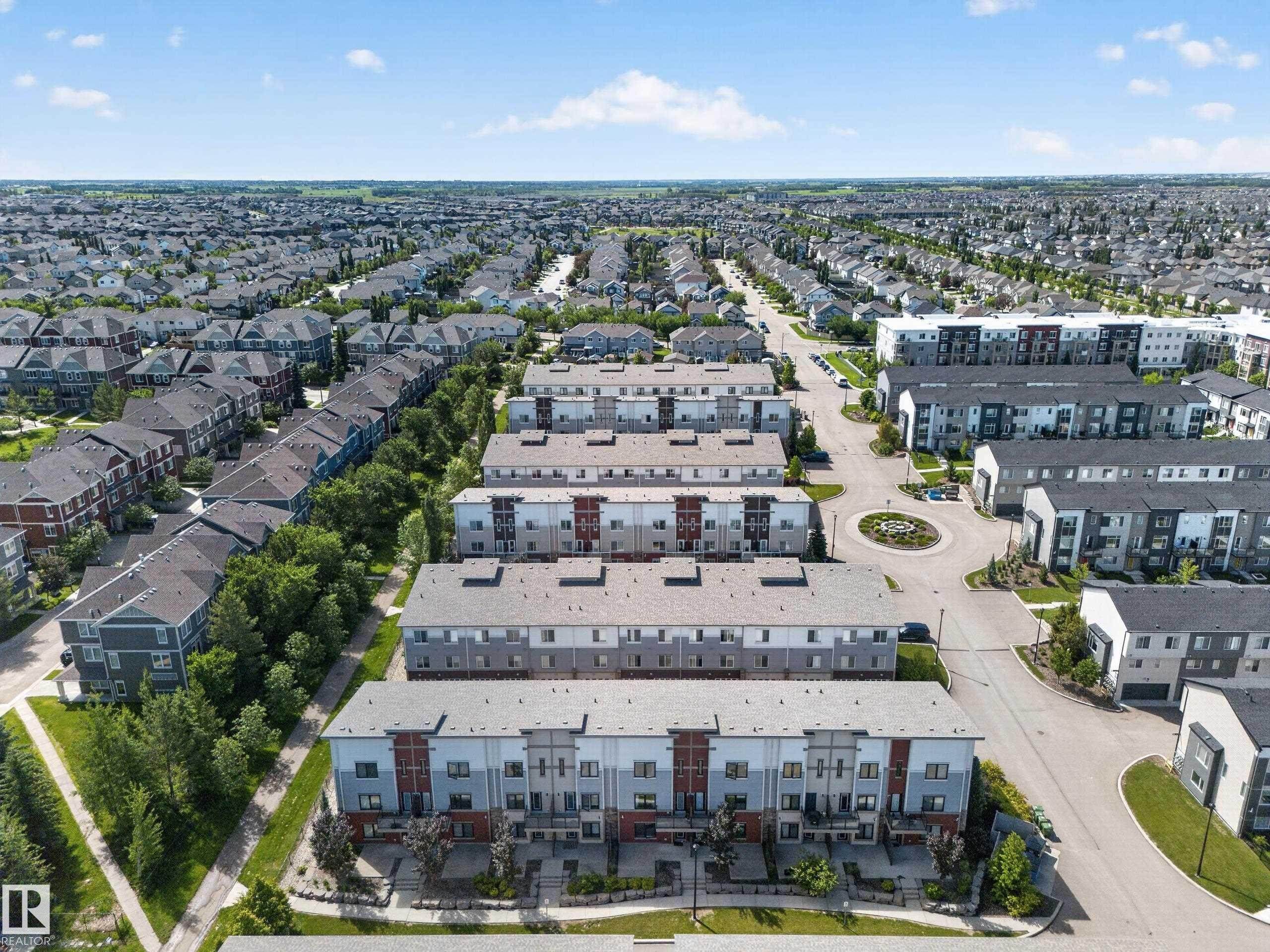 Modern townhome community featuring multi-level facades, integrated garages, and private balconies - #100 804 Welsh Dr Sw, Edmonton, AB - Outdoor With View