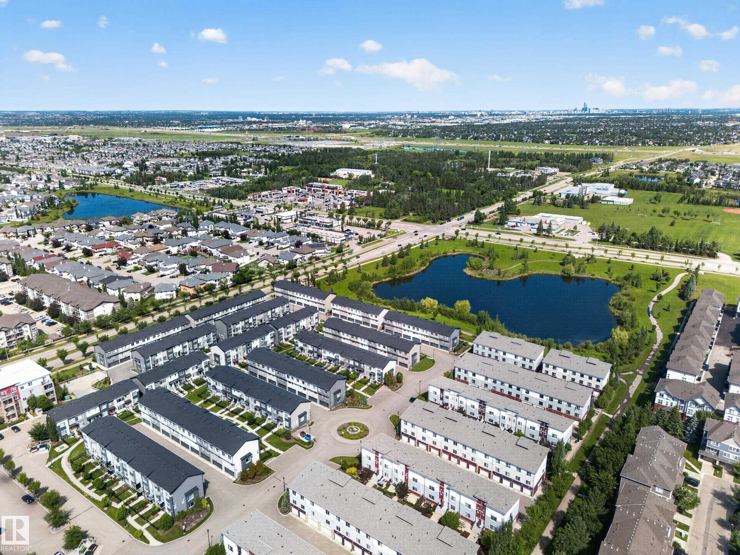 Aerial perspective showcasing a modern townhome community with uniform architecture and dark-pitched roofs - #100 804 Welsh Dr Sw, Edmonton, AB - Outdoor With View